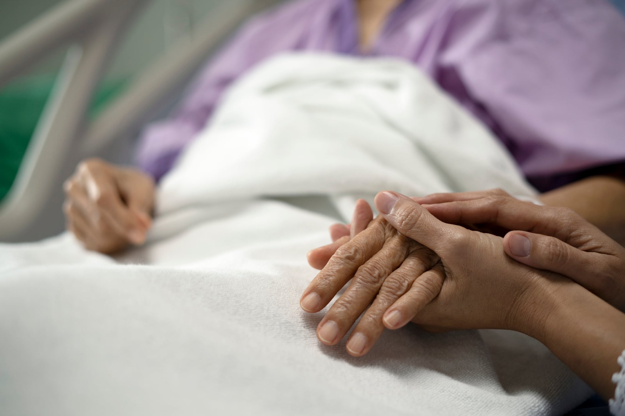 Una paciente en un hospital a la que le coge la mano una acompañante