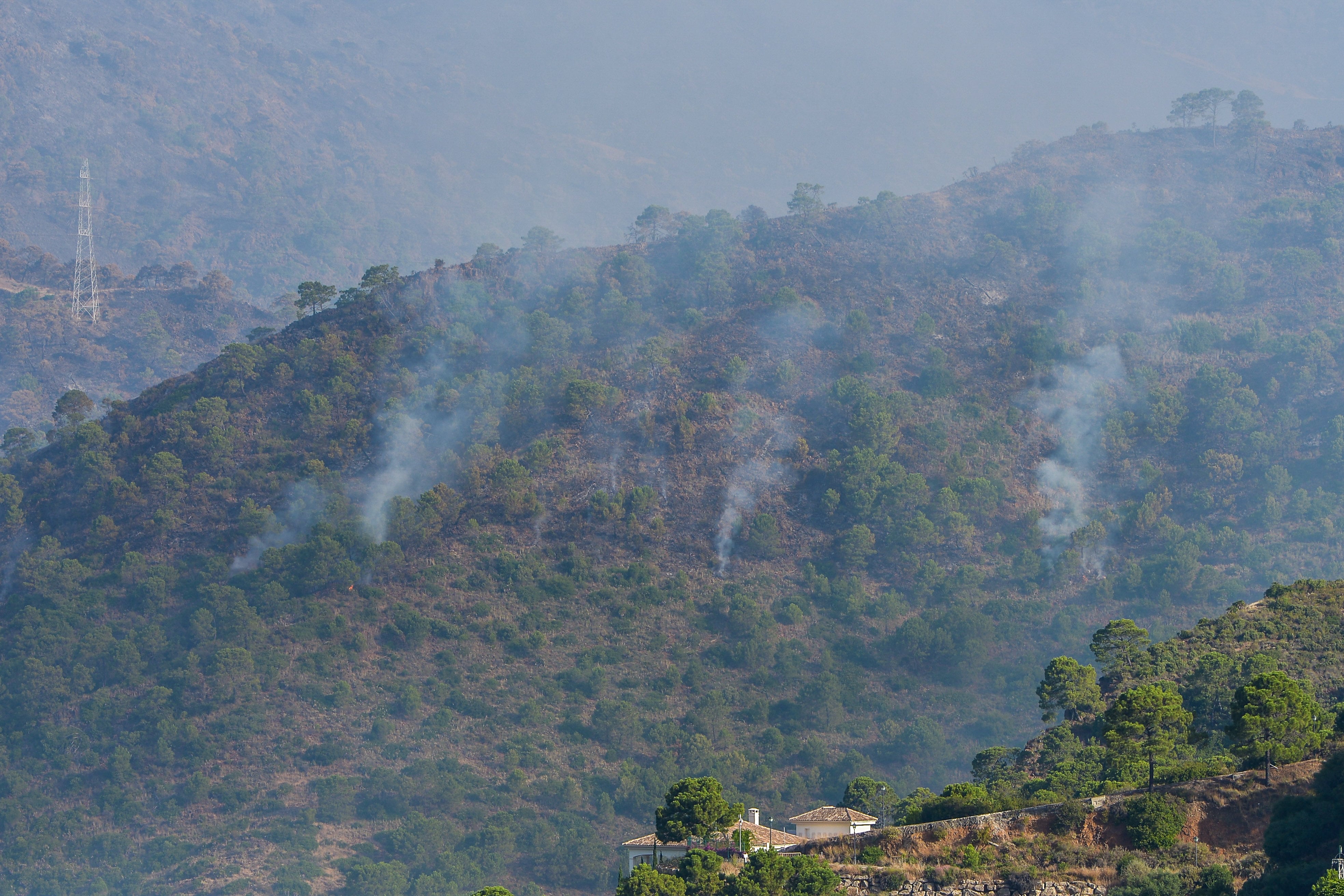 GRAF062. PUJERRA (MÁLAGA), 11/06/2022.- Humo y rescoldos permanecen todavía en el aire tras el incendio acontecido ayer en Pujerra (Málaga), que obligó a desalojar a unas 2.000 personas y que afectó a unas 3.000 hectáreas, este sábado desde la zona residencial de Monte Mayor. EFE/Antonio Paz
