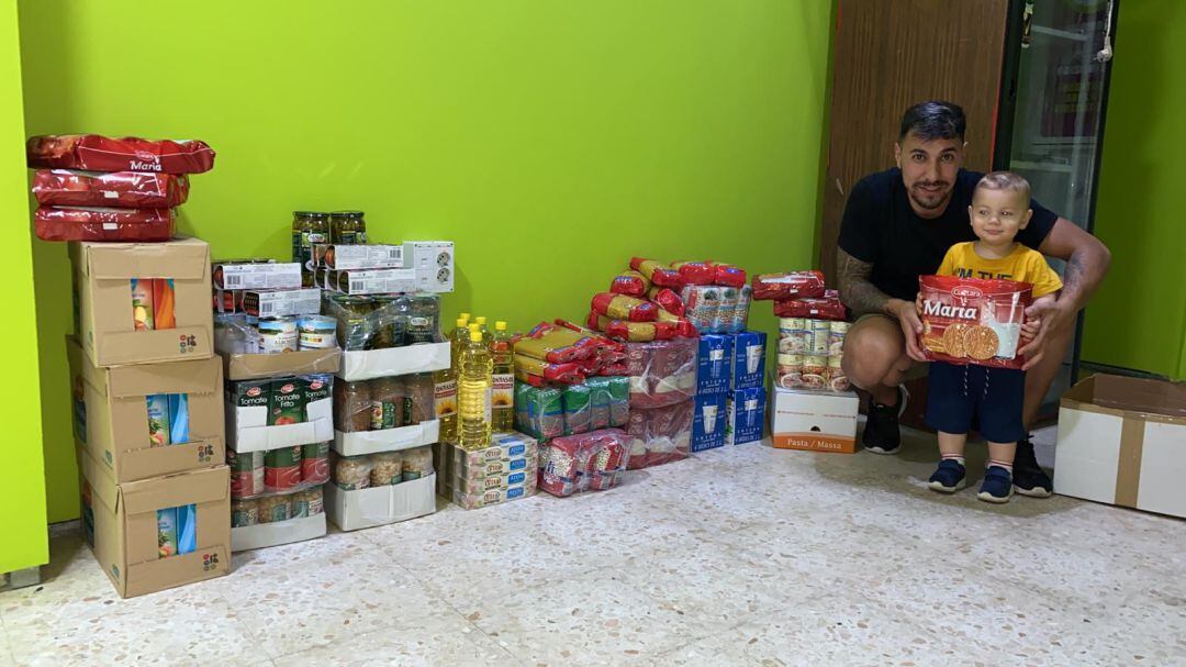 Dani Castro con su hijo junto al lote de alimentos que dona el club 