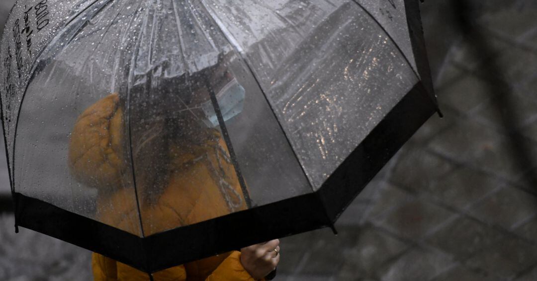 Una persona camina bajo la lluvia protegida con un paraguas en Madrid.