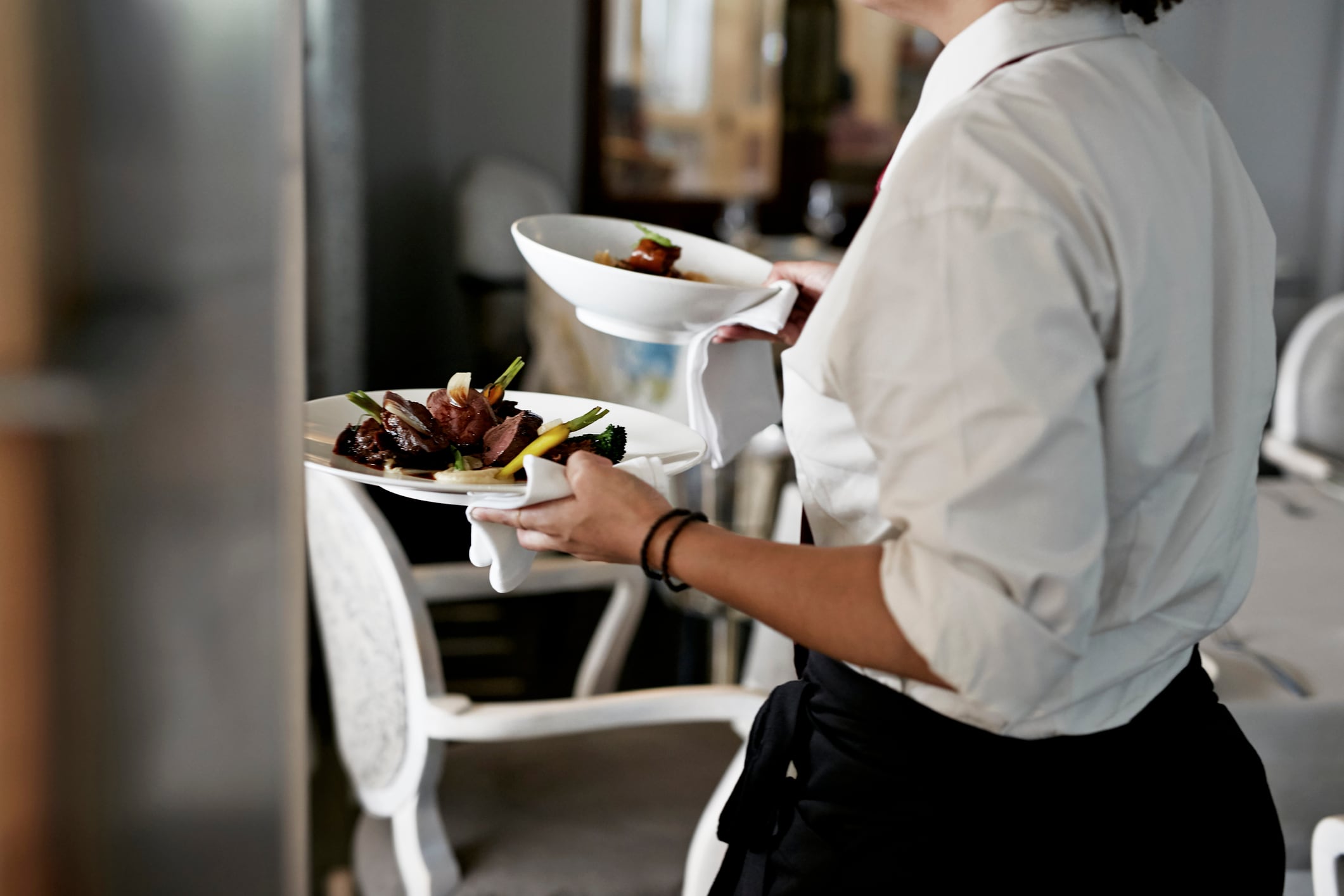 Una trabajadora lleva la comida a la mesa de un cliente en un restaurante