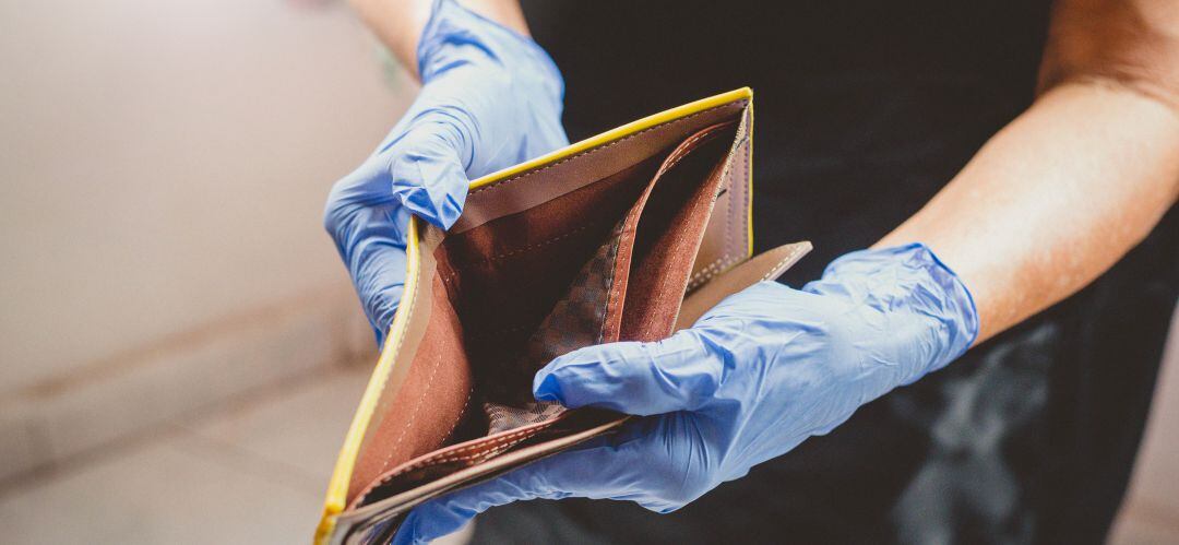 Un autónomo con las manos enguantadas enseña su cartera vacía tras el largo cierre del negocio por el COVID-19