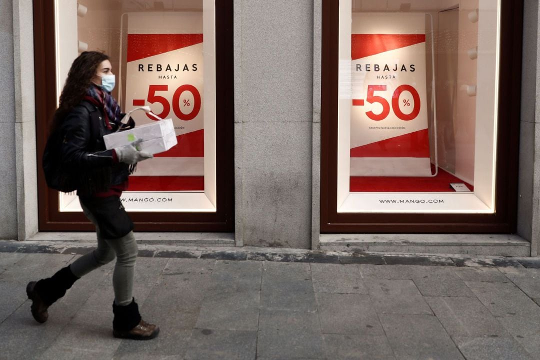 Una mujer pasa frente a un escaparate que anuncia rebajas