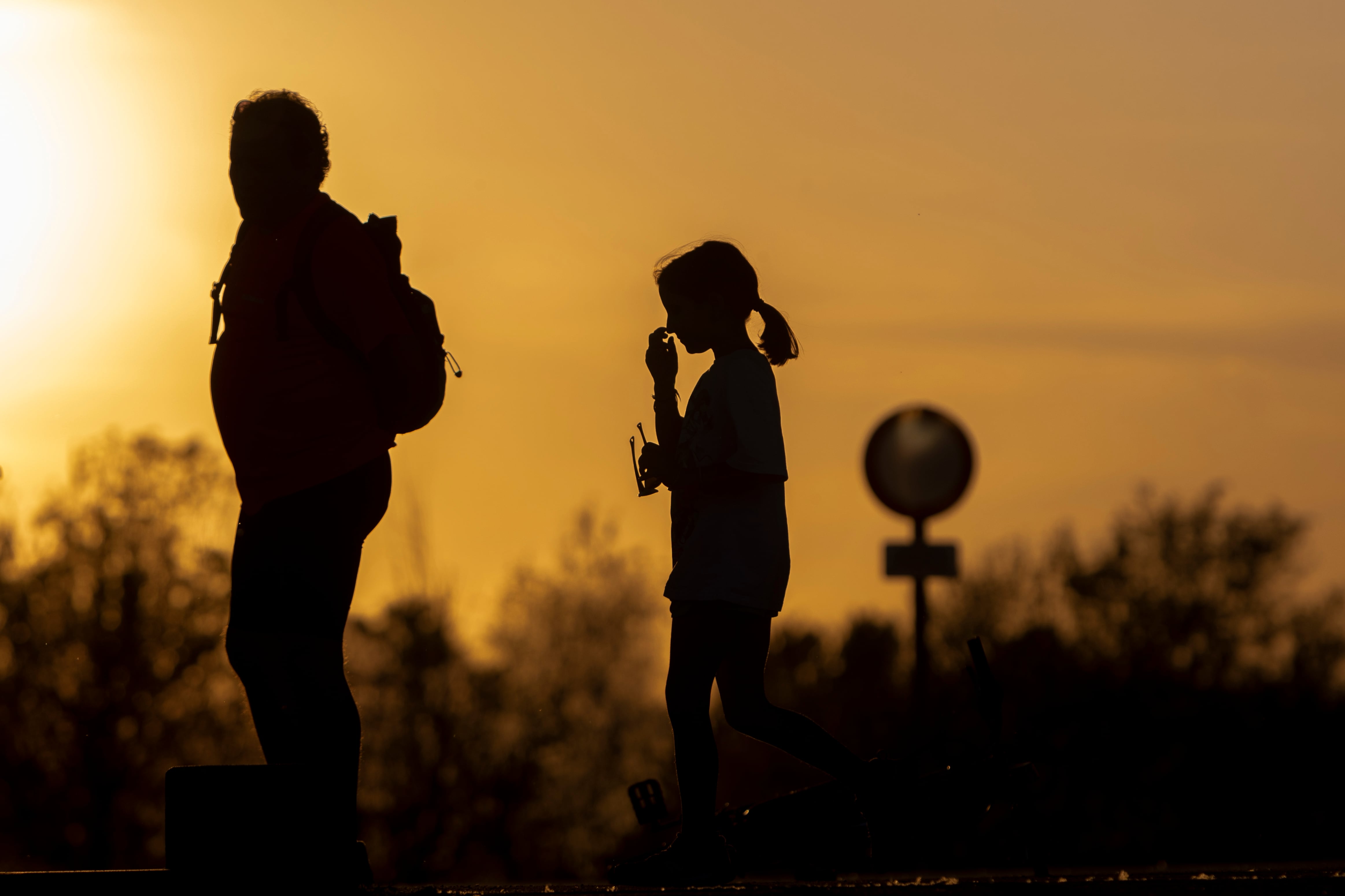 Varias personas pasean por el Parque del Agua de Zaragoza al atardecer.