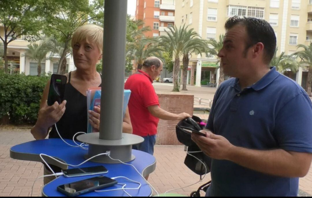 Los concejales Ramón Abad y Puri Vives en el punto de recarga gratuito de móviles