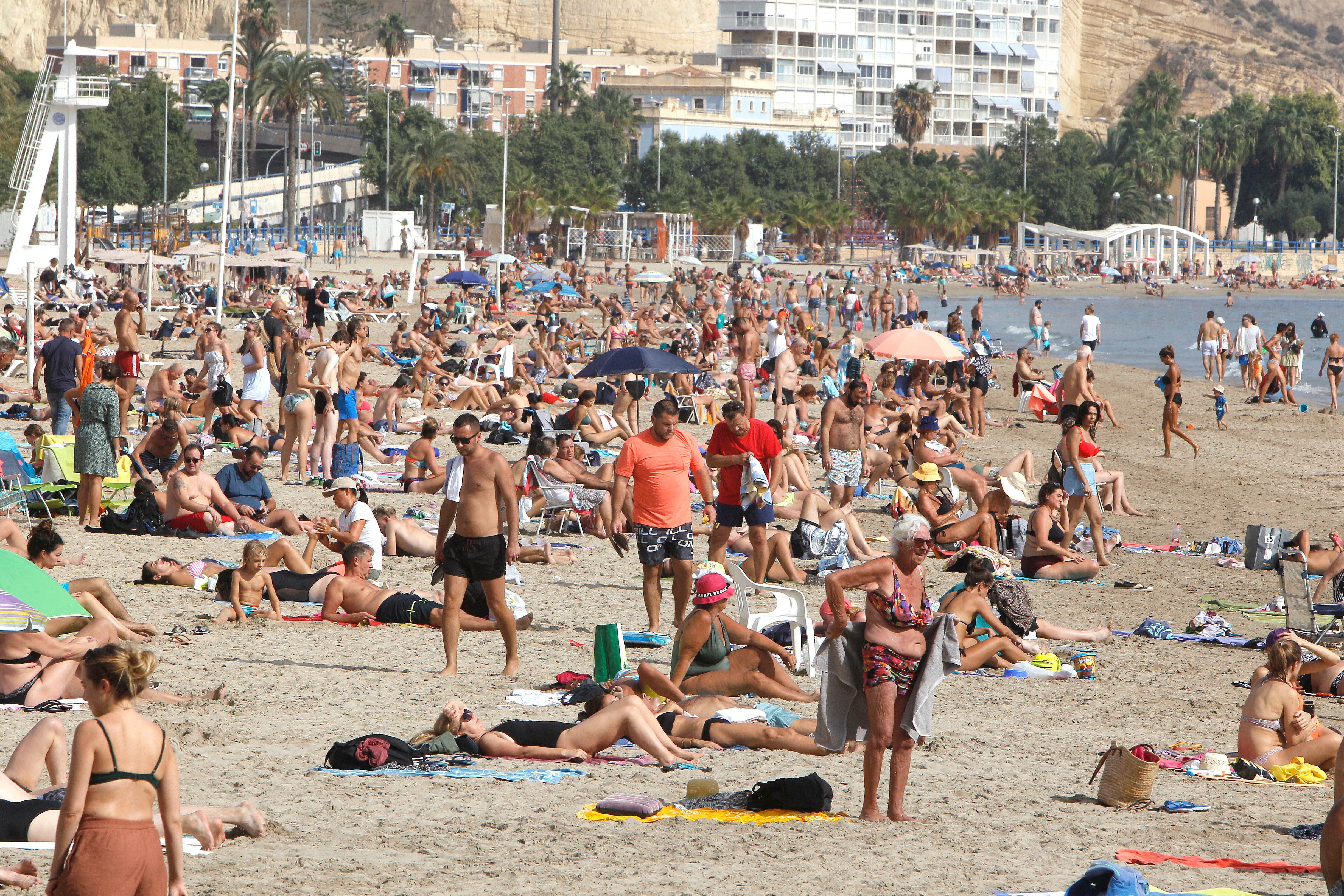 Cientos de personas toman el sol y se bañan en la playa del Postiguet de Alicante