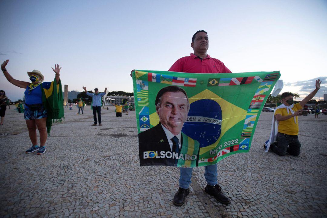 Seguidores del presidente de Brasil, Jair Bolsonaro, rezan hoy durante una protesta contra el cierre comercial dada la pandemia covid-19, en Brasilia (Brasil).