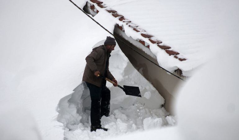 Un hombre limpia su tejado en Bolmir, un pueblo cerca de la localidad cántabra de Reinosa