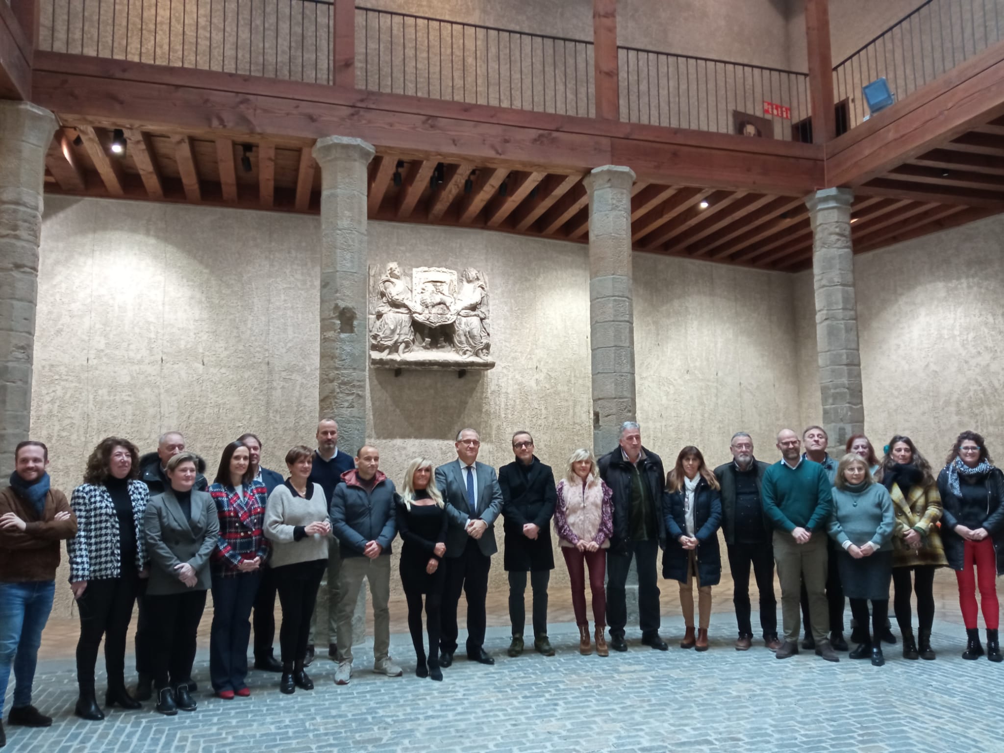 Miembros del Ayuntamiento de Pamplona y la familia Huarte Solchaga bajo la escultura con el escudo de la capital navarra del siglo XVI