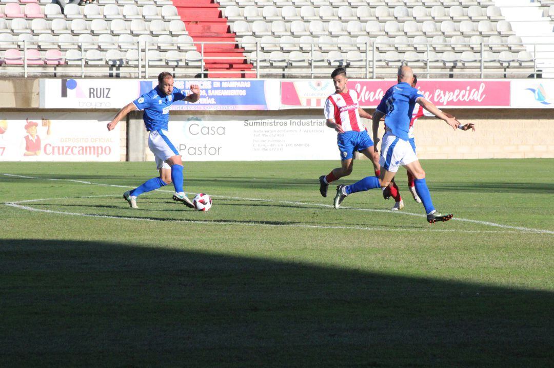 Javi Tamayo conduciendo la pelota ante la atenta mirada de Casares