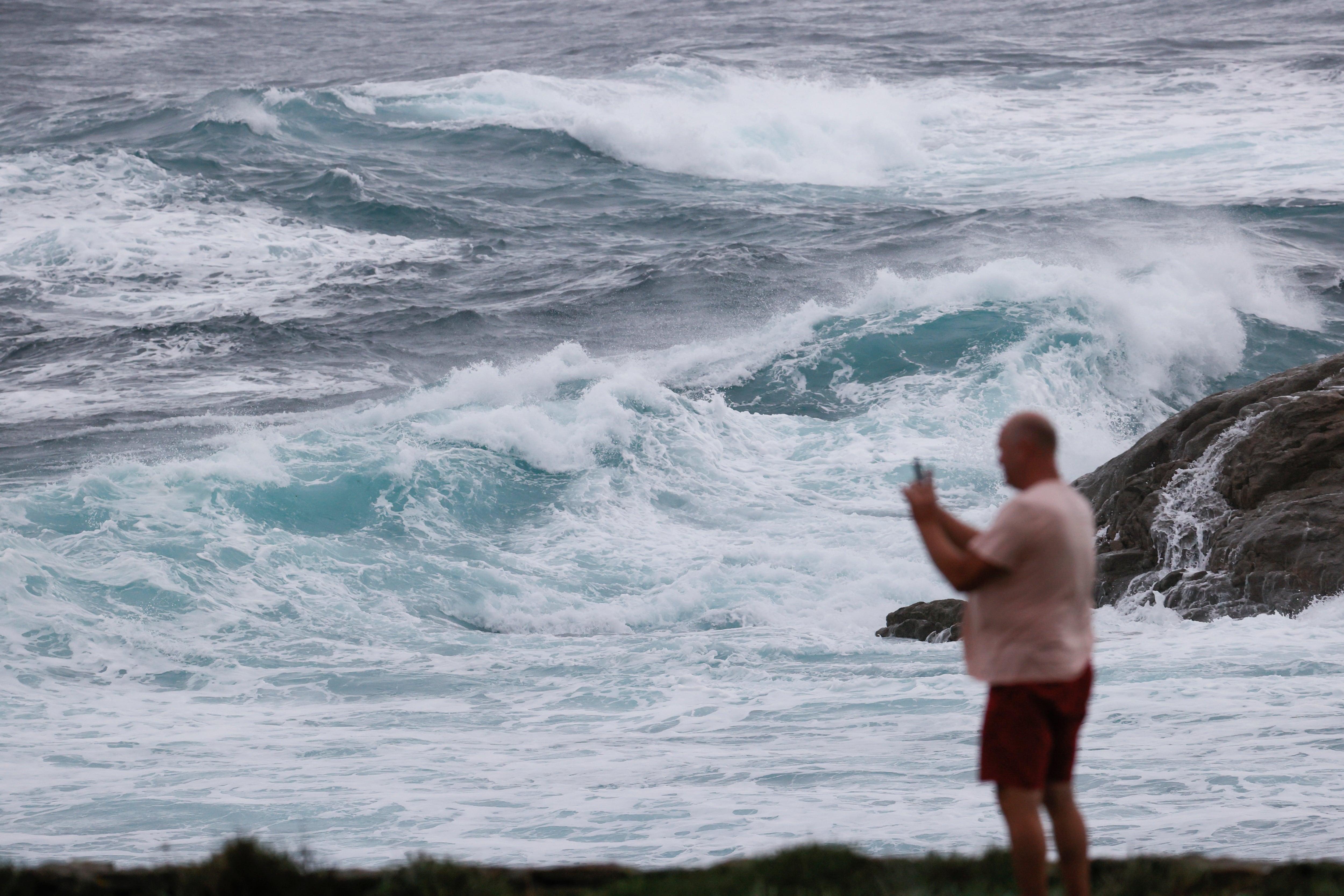 Un turista fotografía las olas en Muxía