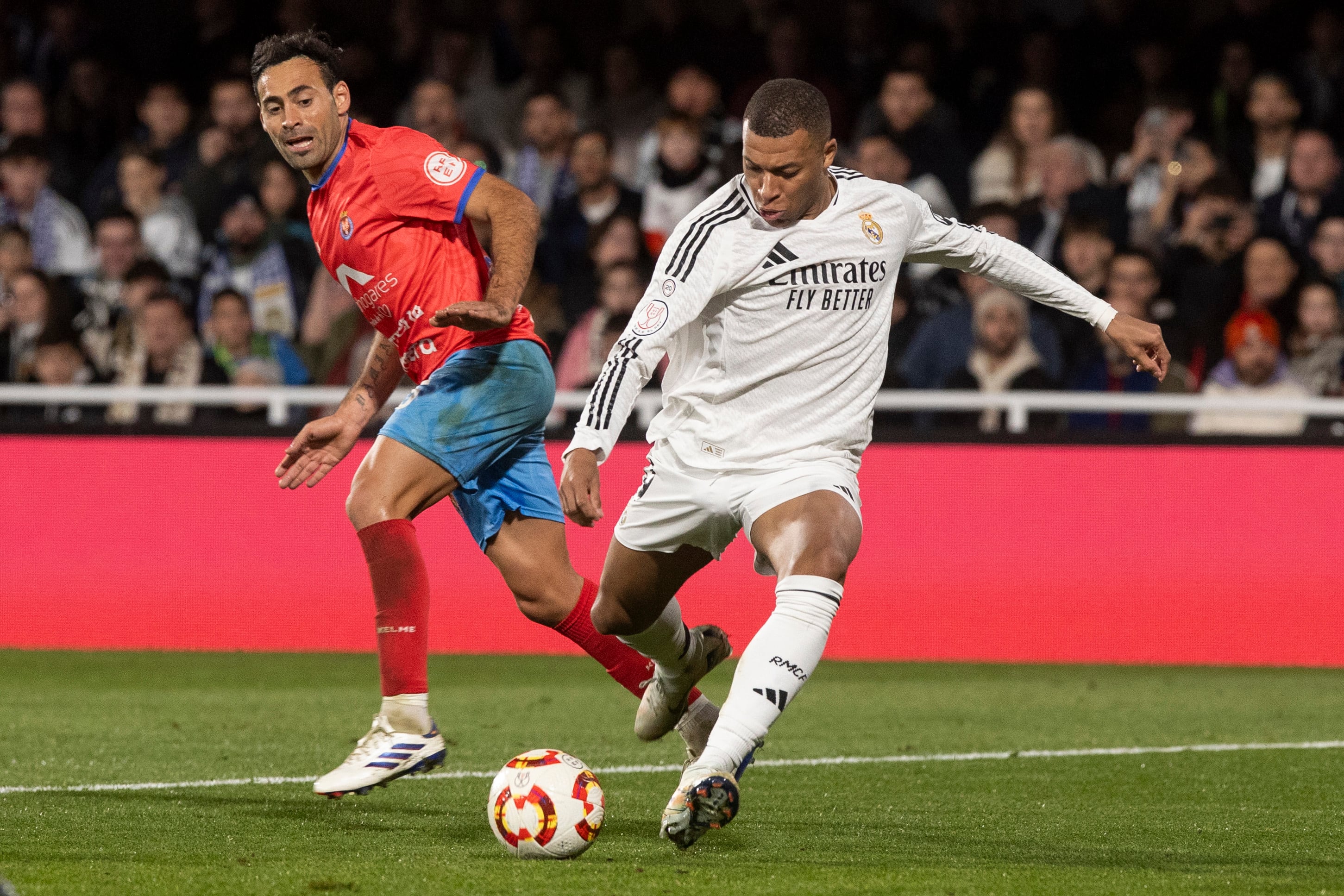 El delantero francés del Real Madrid Kylian Mbappé (d) dispara a puerta ante el jugador de la Deportiva Minera Omar Perdomo (i).