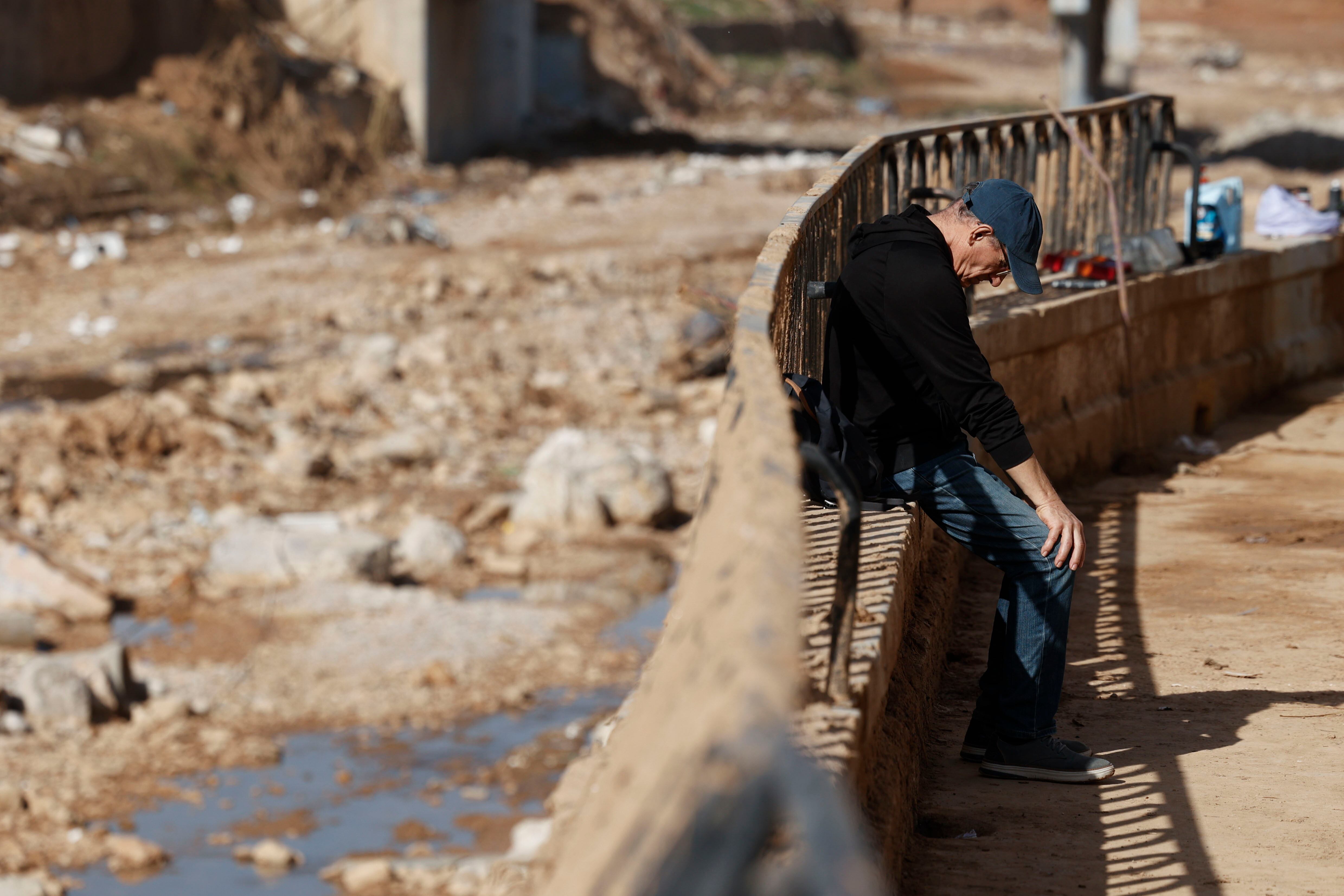 PAIPORTA (VALENCIA), 18/11/2024.- Un hombre toma un descanso junto al barranco del Poyo a su paso por Paiporta, este lunes. Una decena de centros educativos de municipios de la zona cero de la dana que asoló Valencia hace veinte días reinician sus clases en otro paso del lento camino hacia una cierta normalidad para las familias afectadas, mientras empresas y trabajadores reciben asesoramiento público para afrontar las consecuencias laborales de una tragedia que deja ya 219 víctimas mortales y 13 desaparecidos. EFE/Biel Aliño