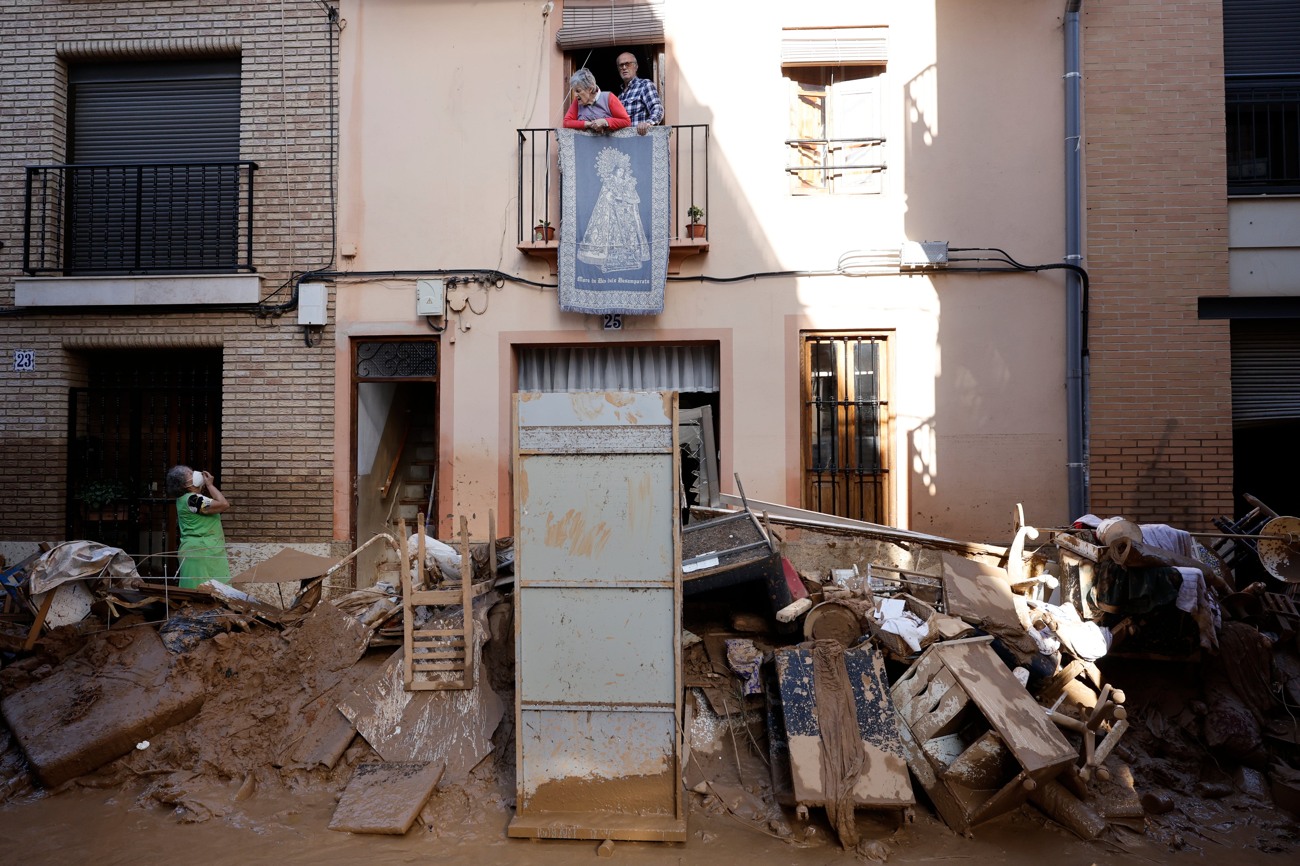 PAIPORTA (VALENCIA), 02/11/2024.- Un vecina habla desde su ventana al no poder salir de su vienda por el bloqueo de la puerta en la localidad valenciana de Paiporta, este sábado. Por tercer día consecutivo una marea de voluntarios ha llegado este sábado a barrios del sur de la ciudad de València y a los pueblos de la comarca vecina de lHorta Sud asolados por la dana para luchar contra un fango, donde grupos especializados de los equipos de intervención buscan cadáveres en garajes o fosos aún anegados.EFE/ Biel Alino
