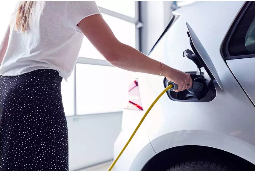 Una mujer carga su coche eléctrico.