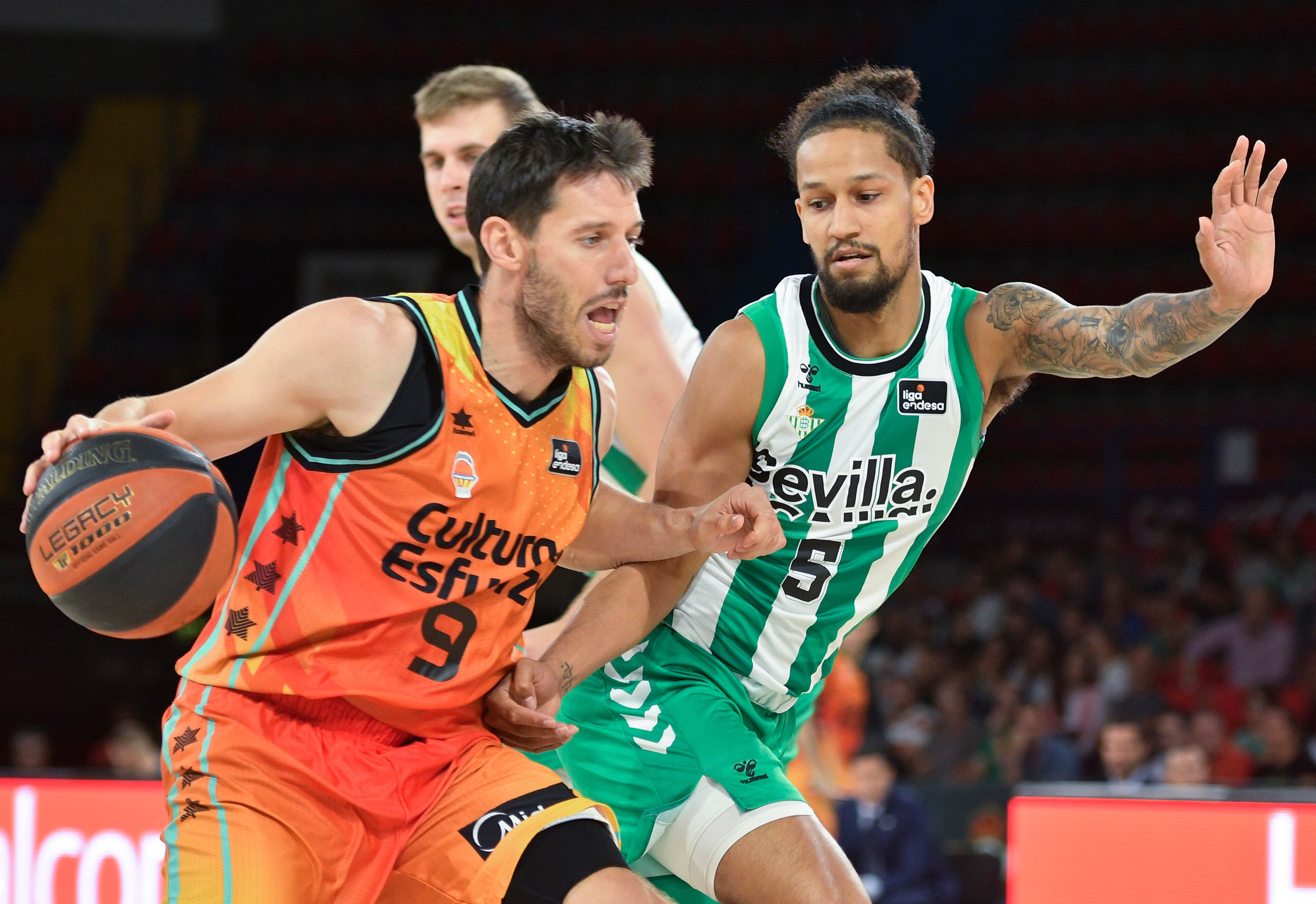 SEVILLA, 30/09/2022.- El base del Real Betis Jeremiah Hill (d) persigue al belga Sam Van Rossom, del Valencia Basket, durante el encuentro perteneciente a la primera jornada de la Liga Endesa disputado hoy viernes en el pabellón San Pablo de Sevilla. EFE/ Raúl Caro.
