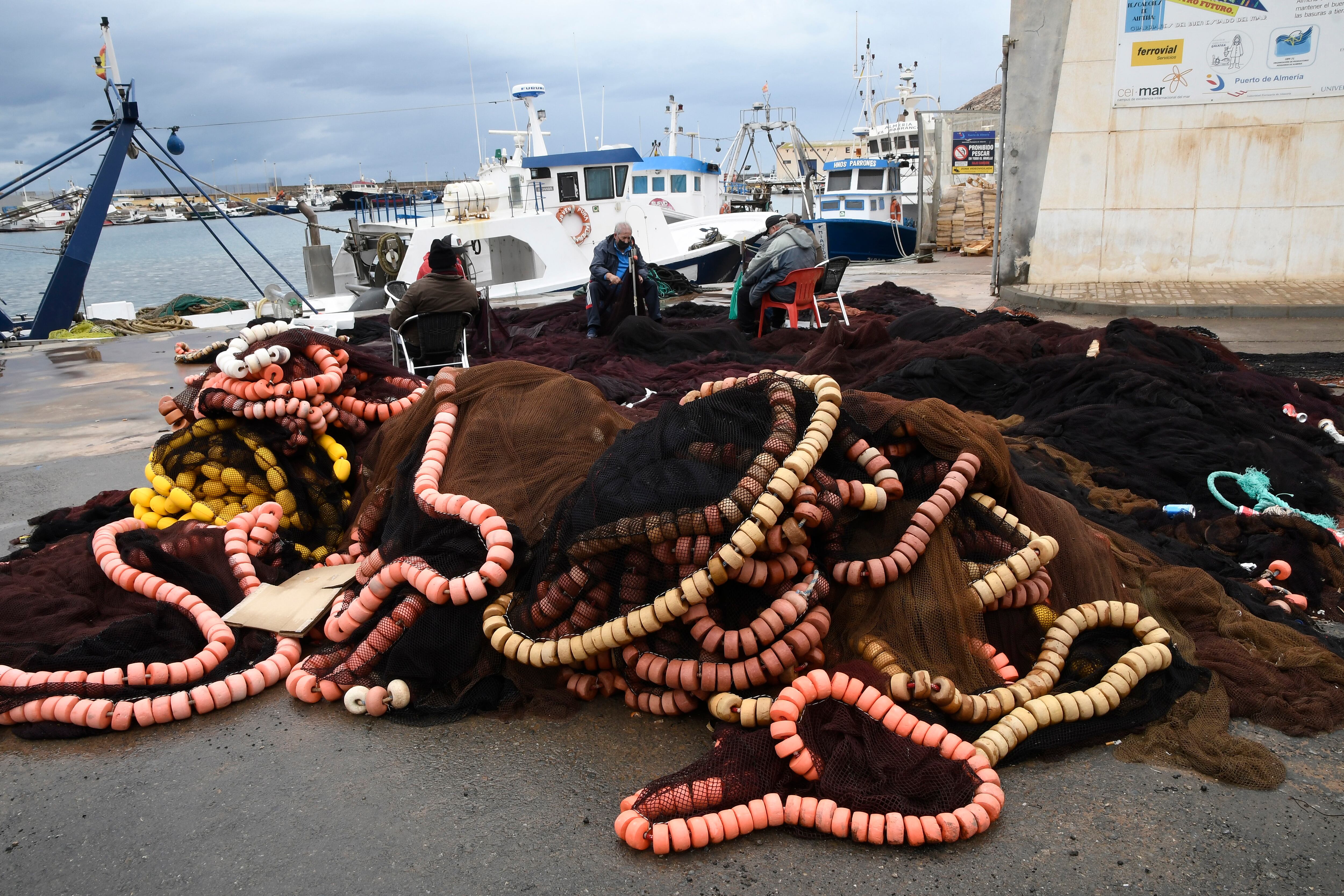 Varios pescadores arreglan los aparejos hoy lunes en el puerto de Almería