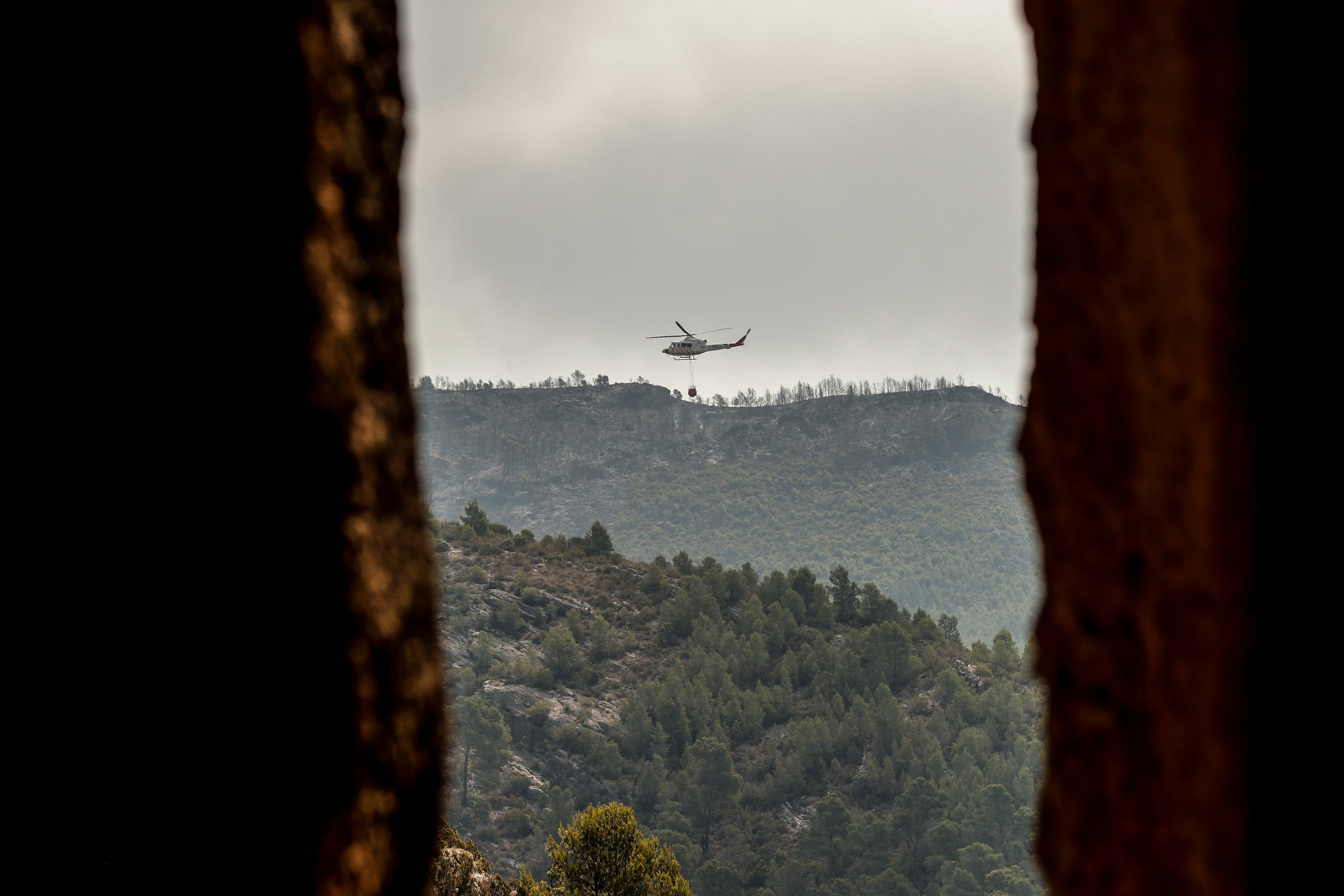 El incendio declarado en la tarde del lunes en una zona boscosa de la localidad valenciana de Calles, en la comarca de Los Serranos, ha calcinado ya unas 230 hectáreas. En la imagen un helicóptero sobrevuela la zona incendiada.