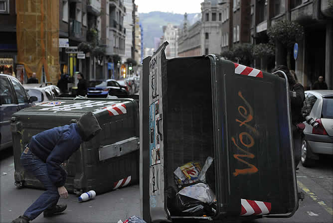 Un grupo de encapuchados vuelcan un contenedor en la calle Doctor Areilza de Bilbao