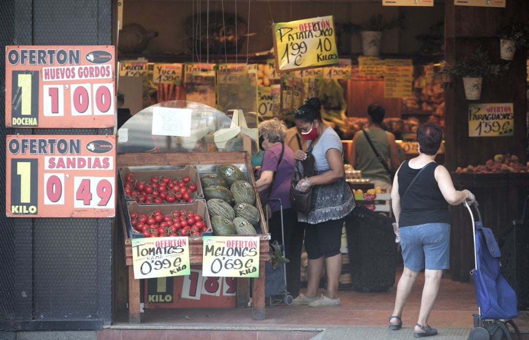 Imagen de archivo de varias personas comprando en una frutería de España.