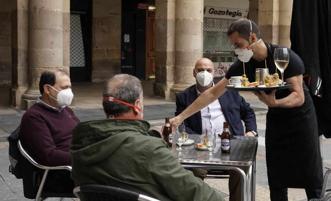 Un camarero atiende a varios clientes en una terraza.