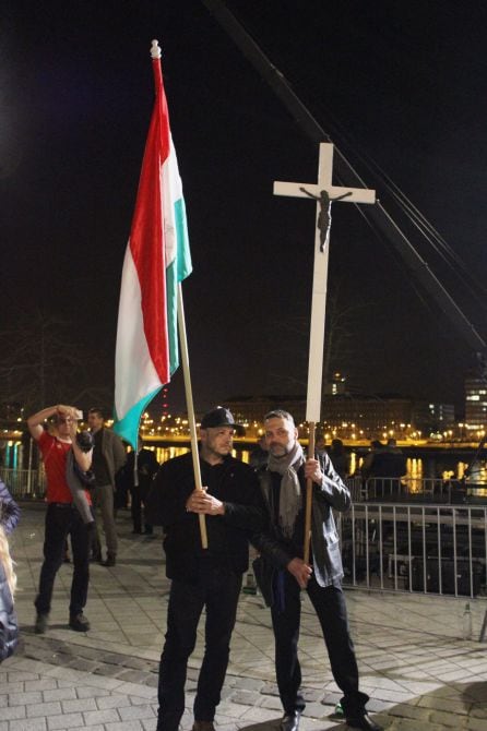 Dos partidarios de Orban con una bandera húngara y un crucifijo