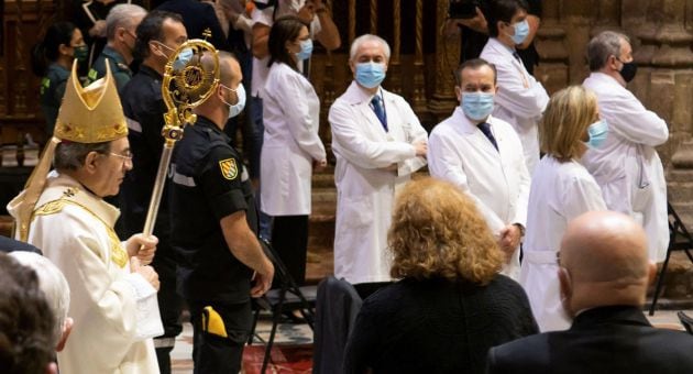 El arzobispo de Sevilla, Juan José Asenjo (i), pasa junto a los representantes de los colectivos de médicos, enfermeros, farmacéuticos, trabajadores de centros de personas mayores, Unidad Militar de Emergencias, Guardia Civil, Policía Nacional, Policía Local, Protección Civil, Bomberos y miembros de Cáritas y de Cruz Roja, en homenaje a las personas que han trabajado en primera linea contra el coronavirus, momentos antes de la celebración de la misa del Corpus Christi en el interior de la Catedral de Sevilla con todas las medidas sanitarias tras suspenderse su procesión por las calles de la capital hispalense