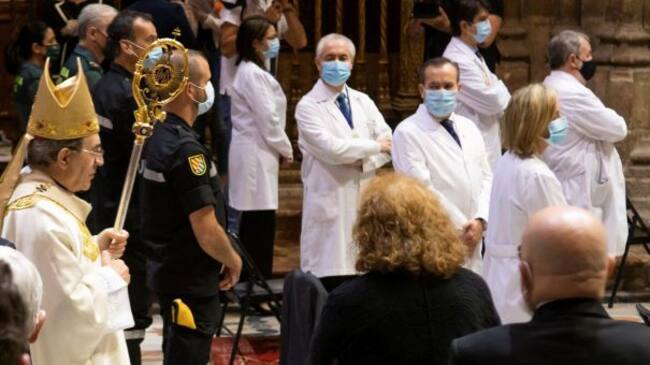 El arzobispo de Sevilla, Juan José Asenjo (i), pasa junto a los representantes de los colectivos de médicos, enfermeros, farmacéuticos, trabajadores de centros de personas mayores, Unidad Militar de Emergencias, Guardia Civil, Policía Nacional, Policía Local, Protección Civil, Bomberos y miembros de Cáritas y de Cruz Roja, en homenaje a las personas que han trabajado en primera linea contra el coronavirus, momentos antes de la celebración de la misa del Corpus Christi en el interior de la Catedral de Sevilla con todas las medidas sanitarias tras suspenderse su procesión por las calles de la capital hispalense
