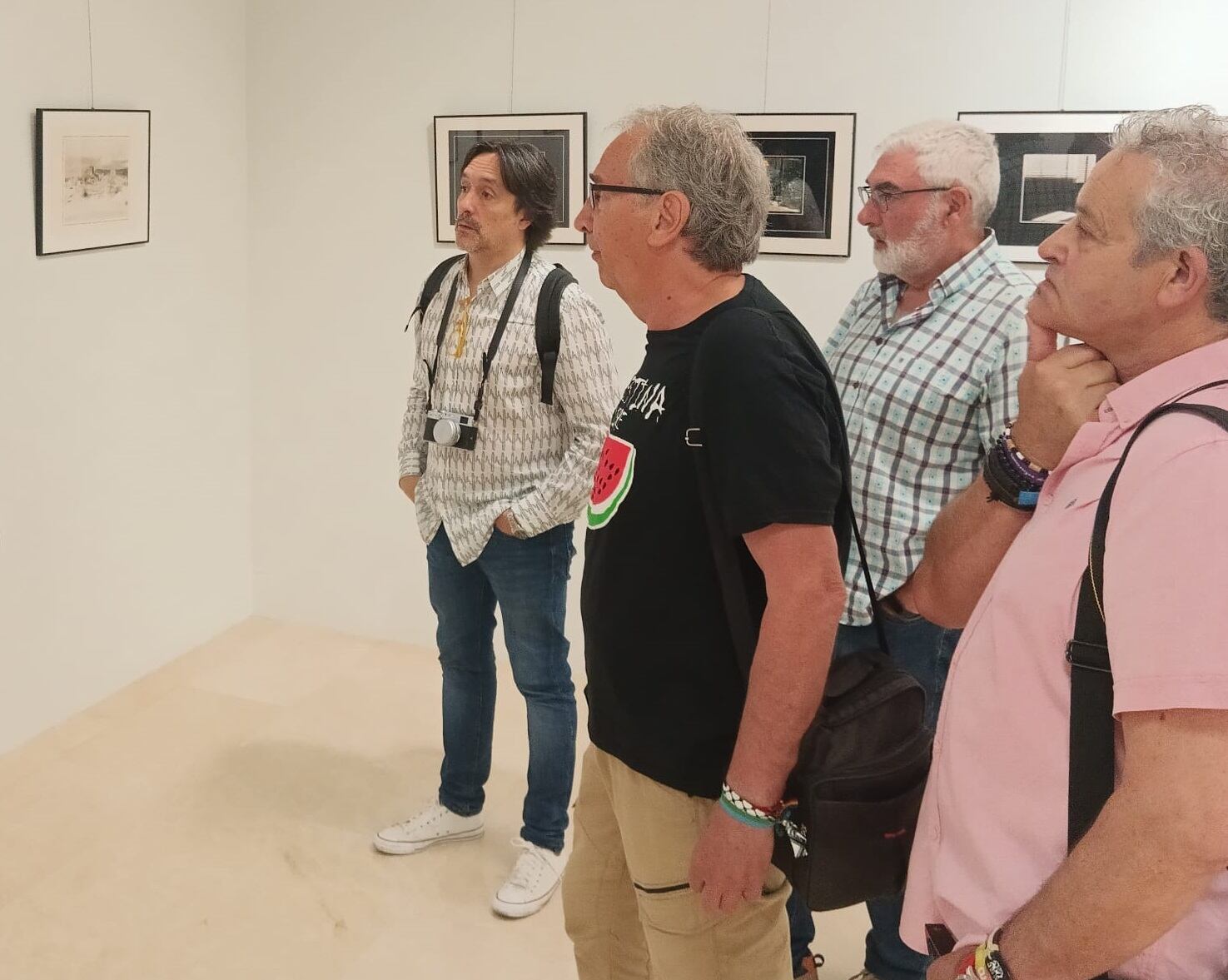 Varios miembros del grupo observan y comentan las imágenes de la exposición