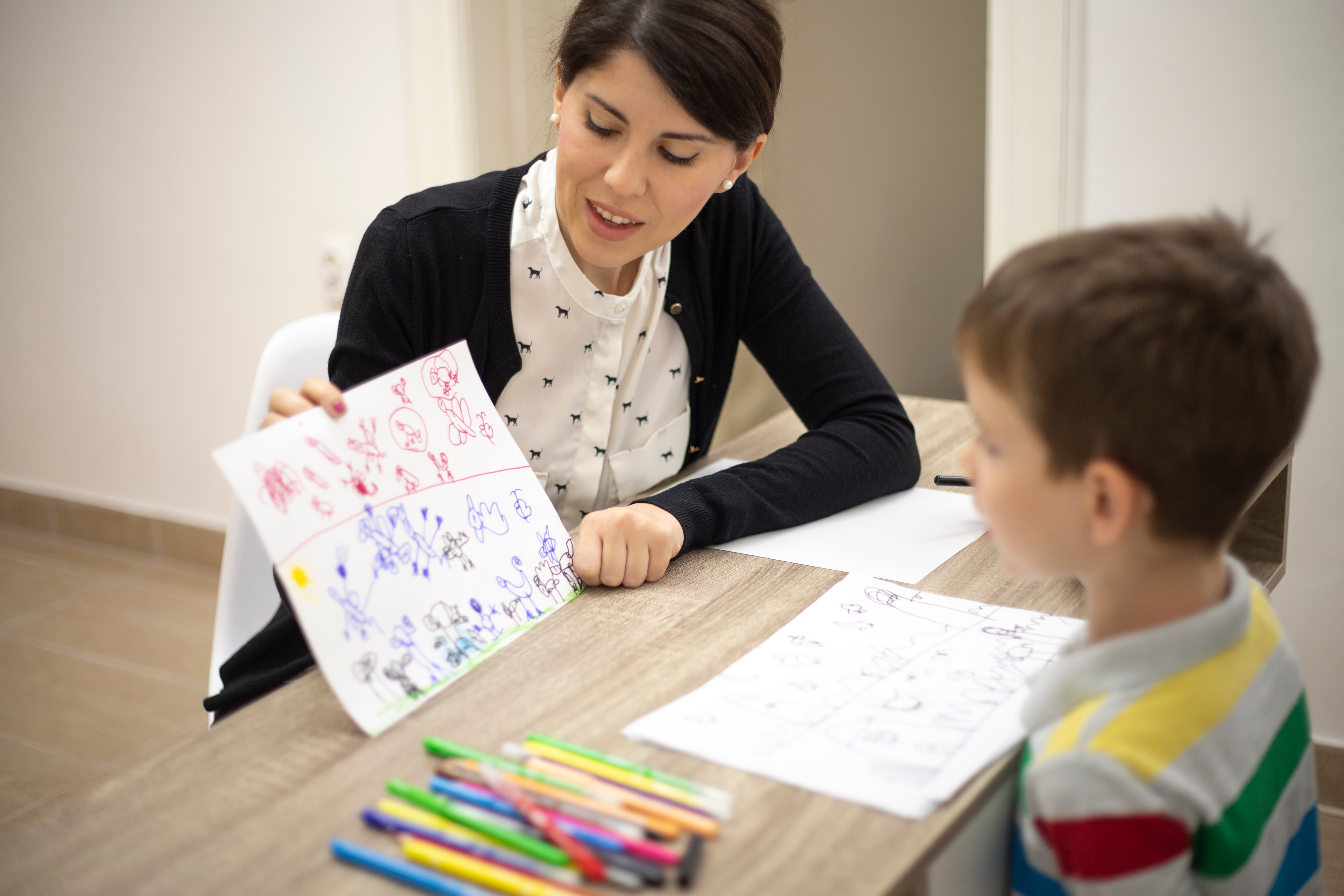 Mujer enseñando pictogramas a un niño TEA