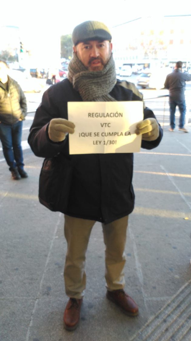 Un taxista muestra un cartel en el que exige que se cumpla la ley.