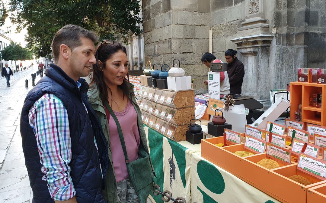 Dos turistas visitan Granada y se detienen ante uno de los puestos de especias en uno de los laterales de la Catedral