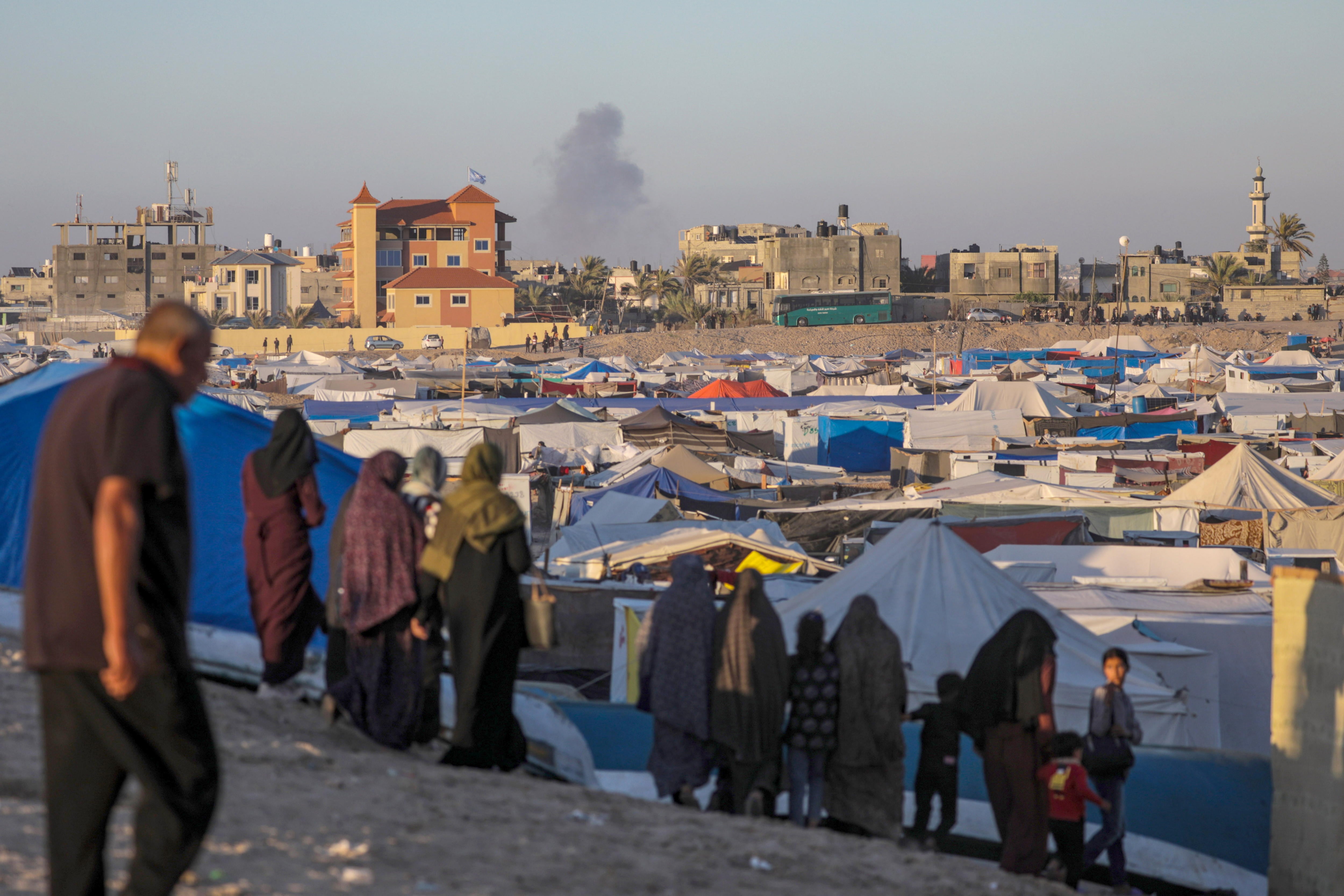 -FOTODELDIA- Rafah (-), 07/05/2024.- Desplazados internos palestinos permanecen en un campamento mientras se eleva humo al fondo tras un ataque aéreo israelí, en Rafah, sur de la Franja de Gaza, 07 de mayo de 2024 (publicado el 08 de mayo de 2024). El 6 de mayo, las Fuerzas de Defensa de Israel (FDI) pidieron a los residentes del este de Rafah que evacuaran &quot;temporalmente&quot; a una zona humanitaria ampliada. EFE/MOHAMMED SABER
