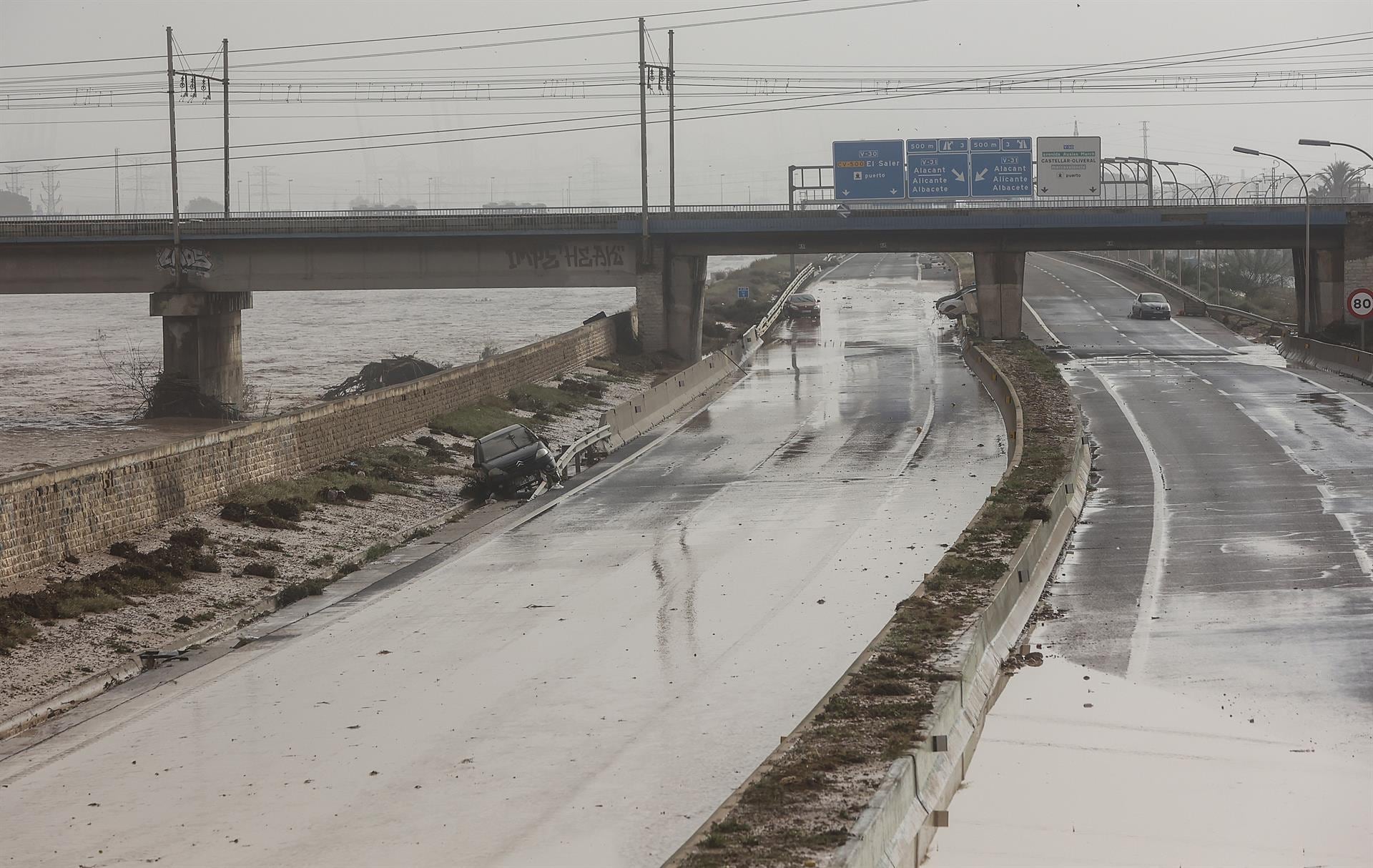 Varias personas recorren calles llenas de agua tras el paso de la DANA por el barrio de La Torre de València