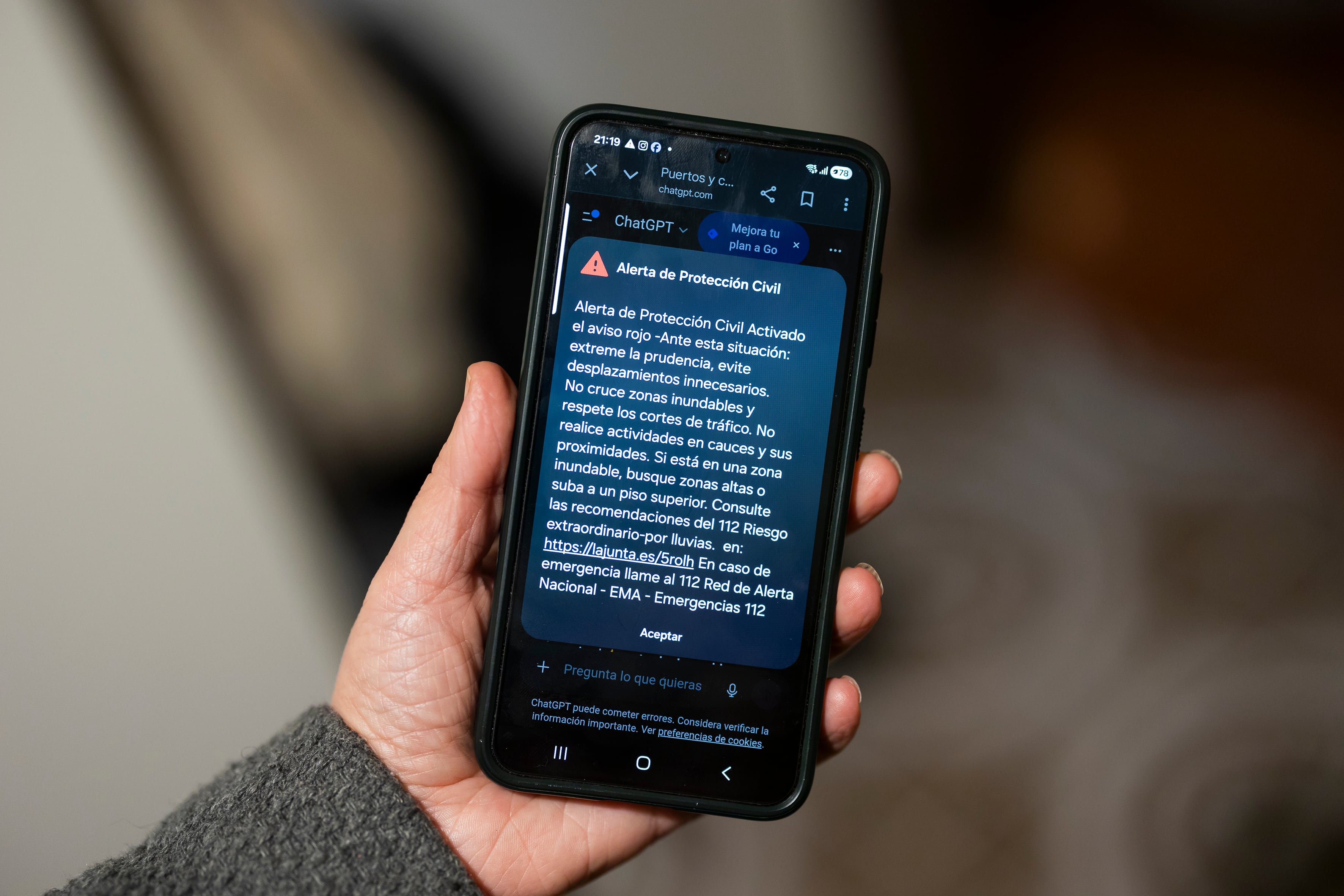 Una persona sostiene un teléfono móvil con la alerta enviada por protección civil de aviso rojo en Málaga. EFE / Carlos Díaz.
