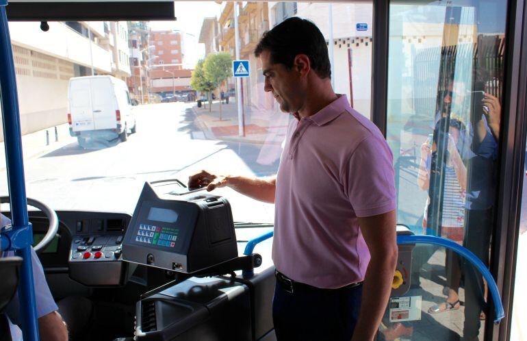 El alcalde, Javier Cuenca, paga el bilete del autobús utilizando el teléfono móvil