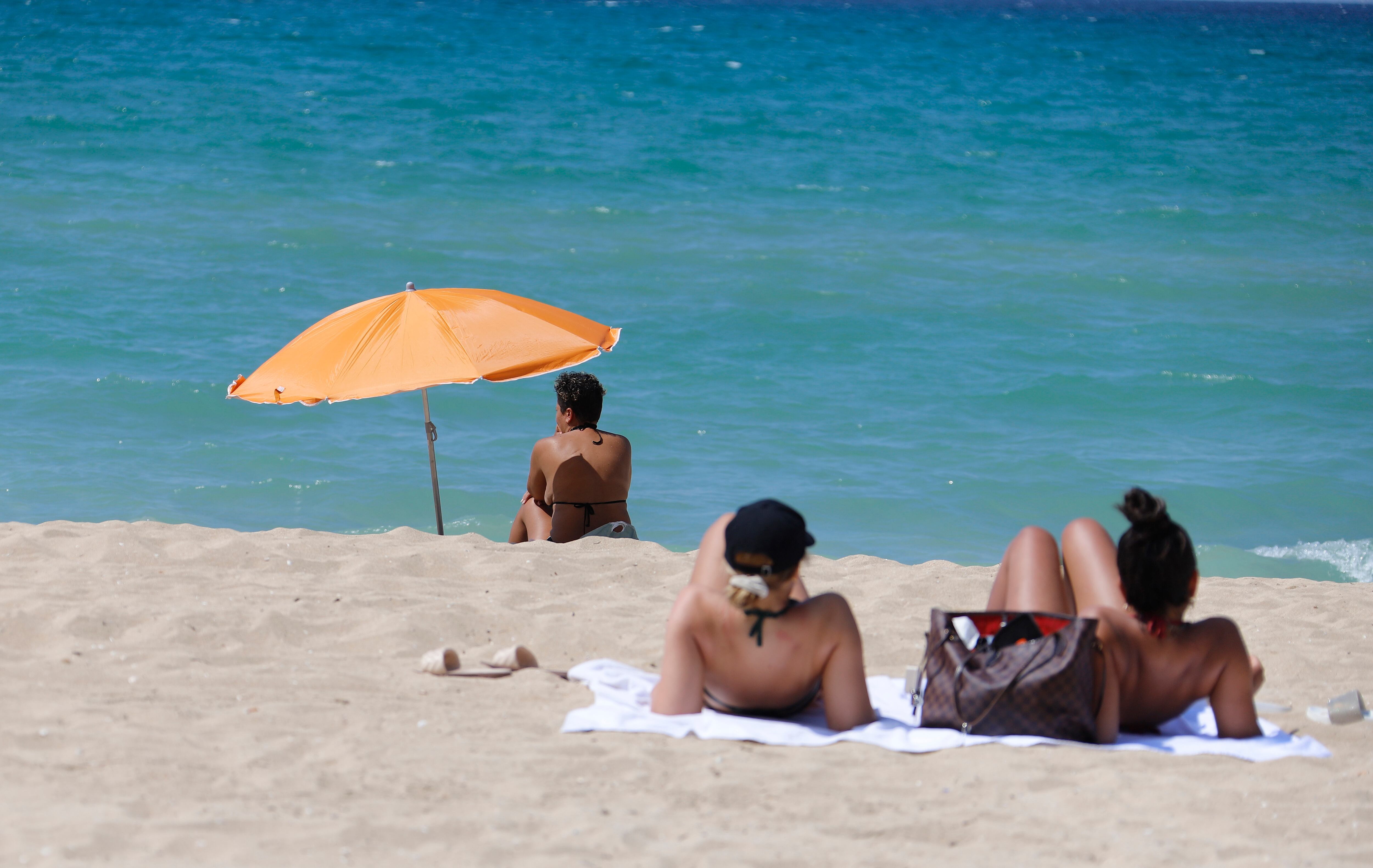 15 August 2020, Spain, Palma: Women sunbathe and swim on the beach of Arenal in Mallorca. In view of the increased risk of infection, the German government has classified almost all of Spain, including Majorca, as a risk area. The classification means that returning holidaymakers are required to test for the coronavirus. Photo: Clara Margais/dpa (Photo by Clara Margais/picture alliance via Getty Images)