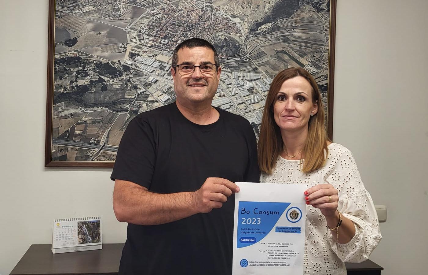 Los ediles Josep Rico, Comercio, y Raquel García, Hacienda, con el cartel que invita a los establecimientos a participar en la campaña del Bono Consumo 2023.