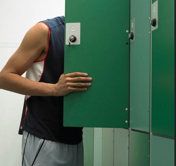 Un hombre revisando una taquilla de un gimnasio.