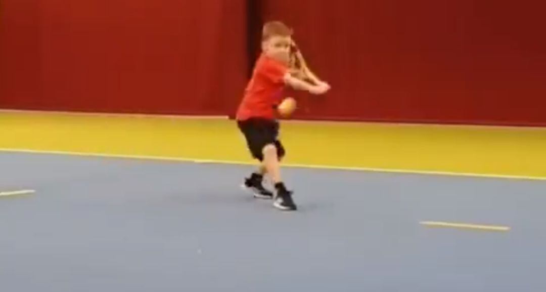 El pequeño Ethan se prepara para golpear la pelota de revés.