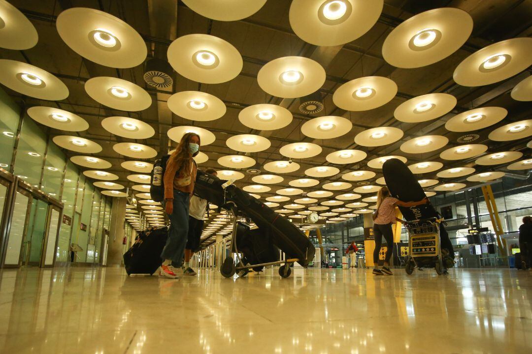 Tres personas transportan su equipaje con carros en la terminal T4 del Aeropuerto Adolfo Suárez Madrid-Barajas, en Madrid (España)