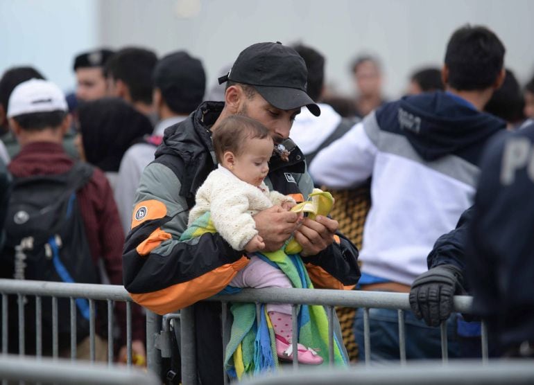Un refugiado con su bebé en brazos mientras hace cola en la frontera entre Hungría y Austria, en Heiligenkreuz (Austria), el 14 de septiembre de 2015. 