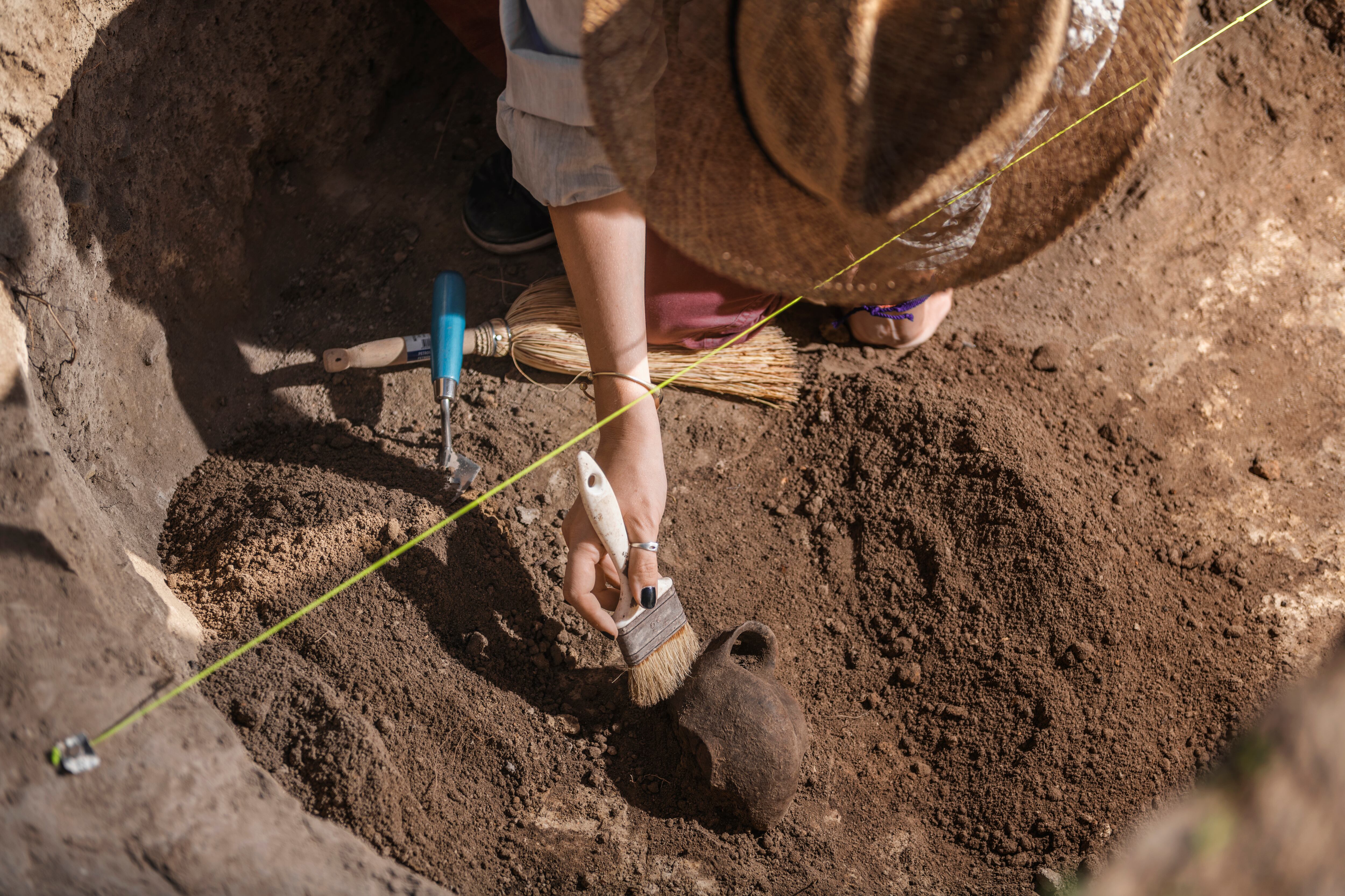 Archaeologist excavating pottery at an archaeological site.