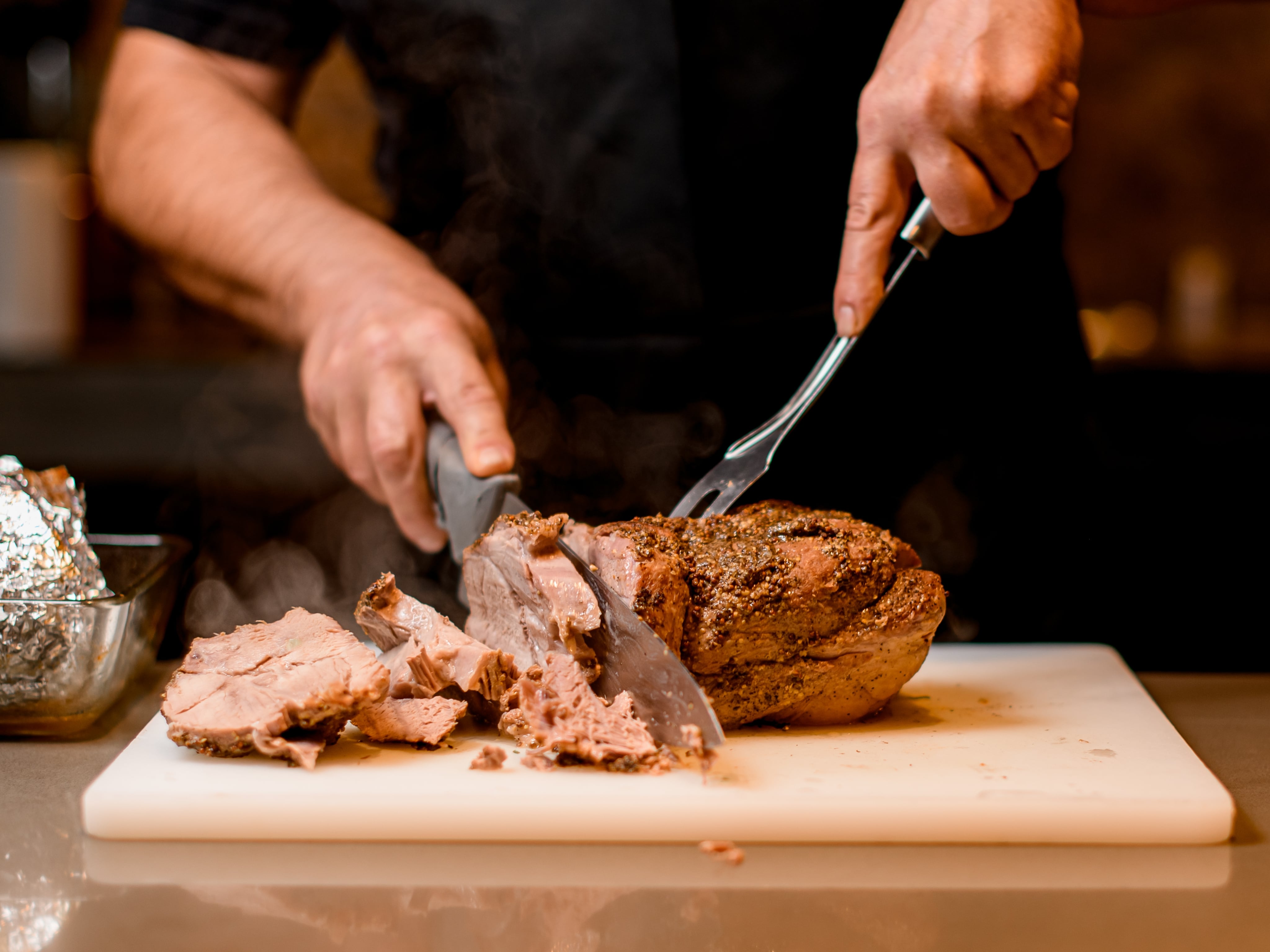 Imagen de un cocinero trinchando carne en la cocina de un restaurante.