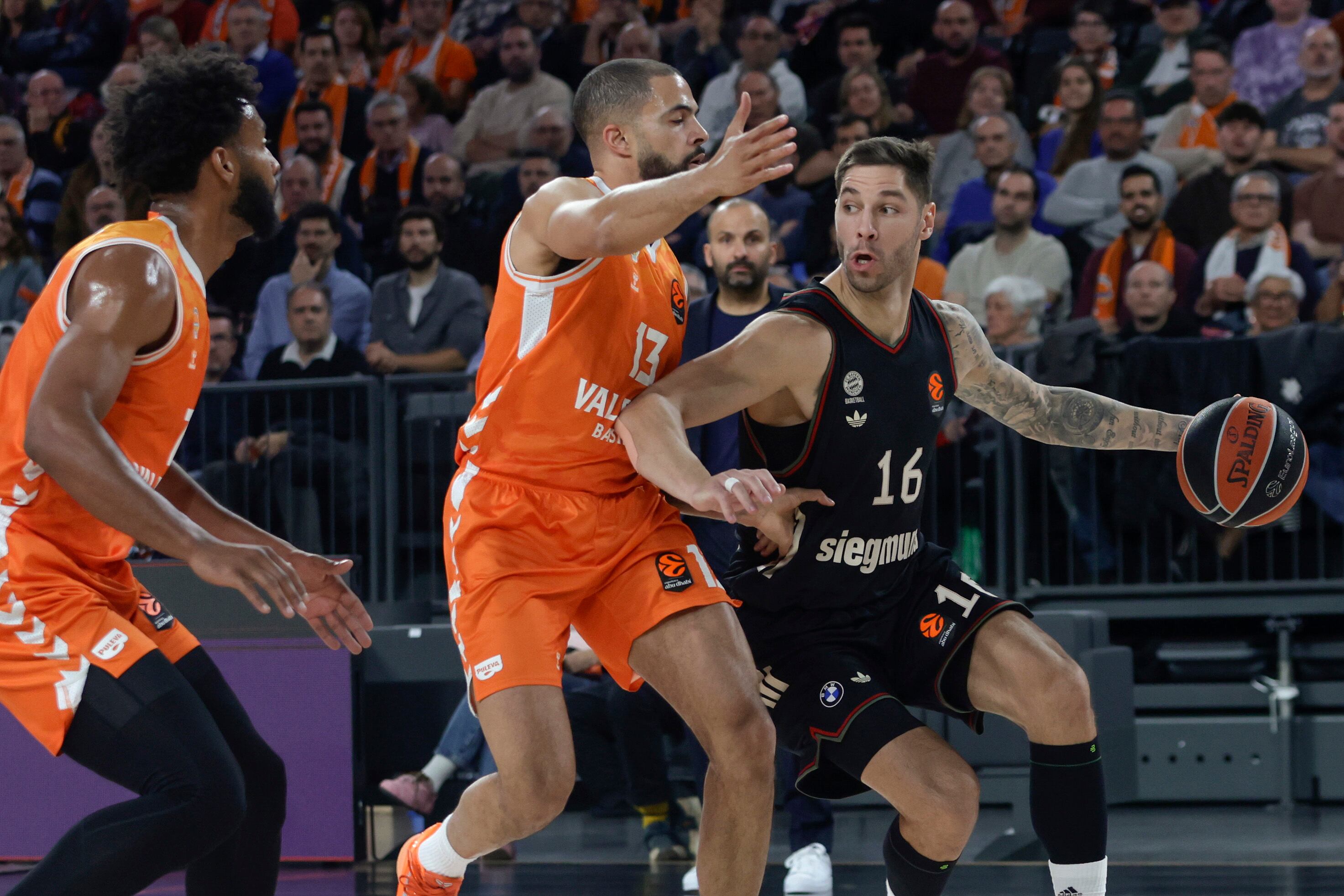 VALENCIA, 25/11/2025.- El base estadounidense con pasaporte italiano del Valencia, Darius Thompson (c) presiona al base serbio del Bayern de Munich Stefan Jovic (d) en el partido de la Euroliga de baloncesto entre el Valencia Basket y el Bayern de Munich, este martes en el Roig Arena. EFE/Miguel Ángel Polo.