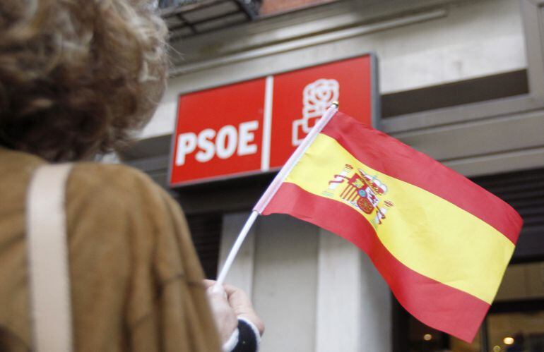 Una persona ondea una bandera española en la sede central del PSOE en la calle Ferraz de Madrid.