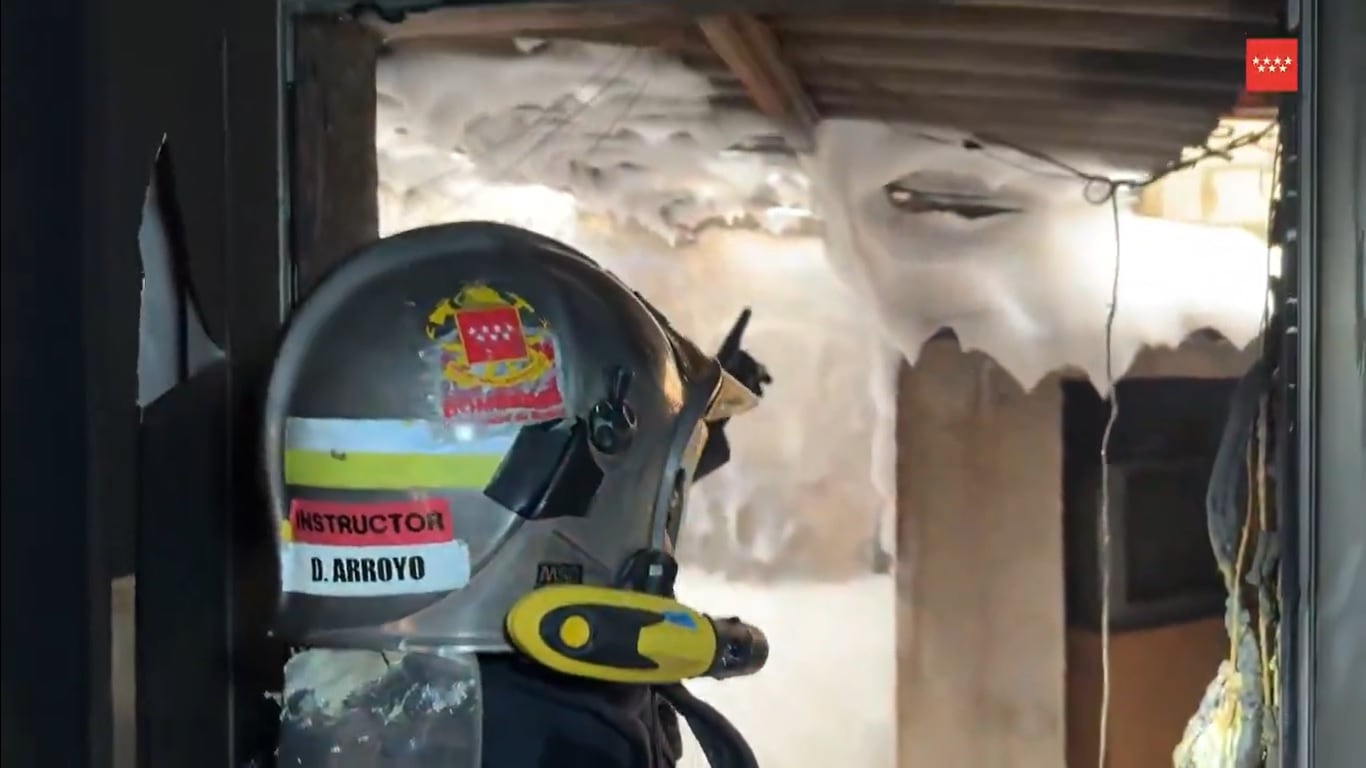 Dos bomberos inspeccionan el interior de la vivienda en la que se produjo el incendio este jueves por la tarde en San Martín de la Vega