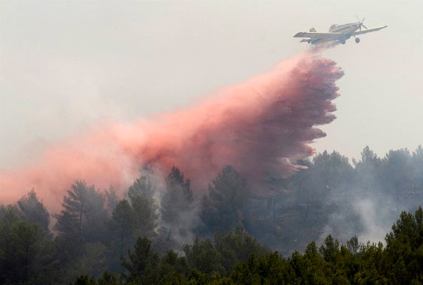 Un medio aéreo descarga en una zona del incendio que se ha reavivado ésta mañana en la Muela de Viver y que desde el pasado jueves ha calcinado parte de las provincias de Valencia y Castellón entre las Sierra Calderona y el Alto Palancia.