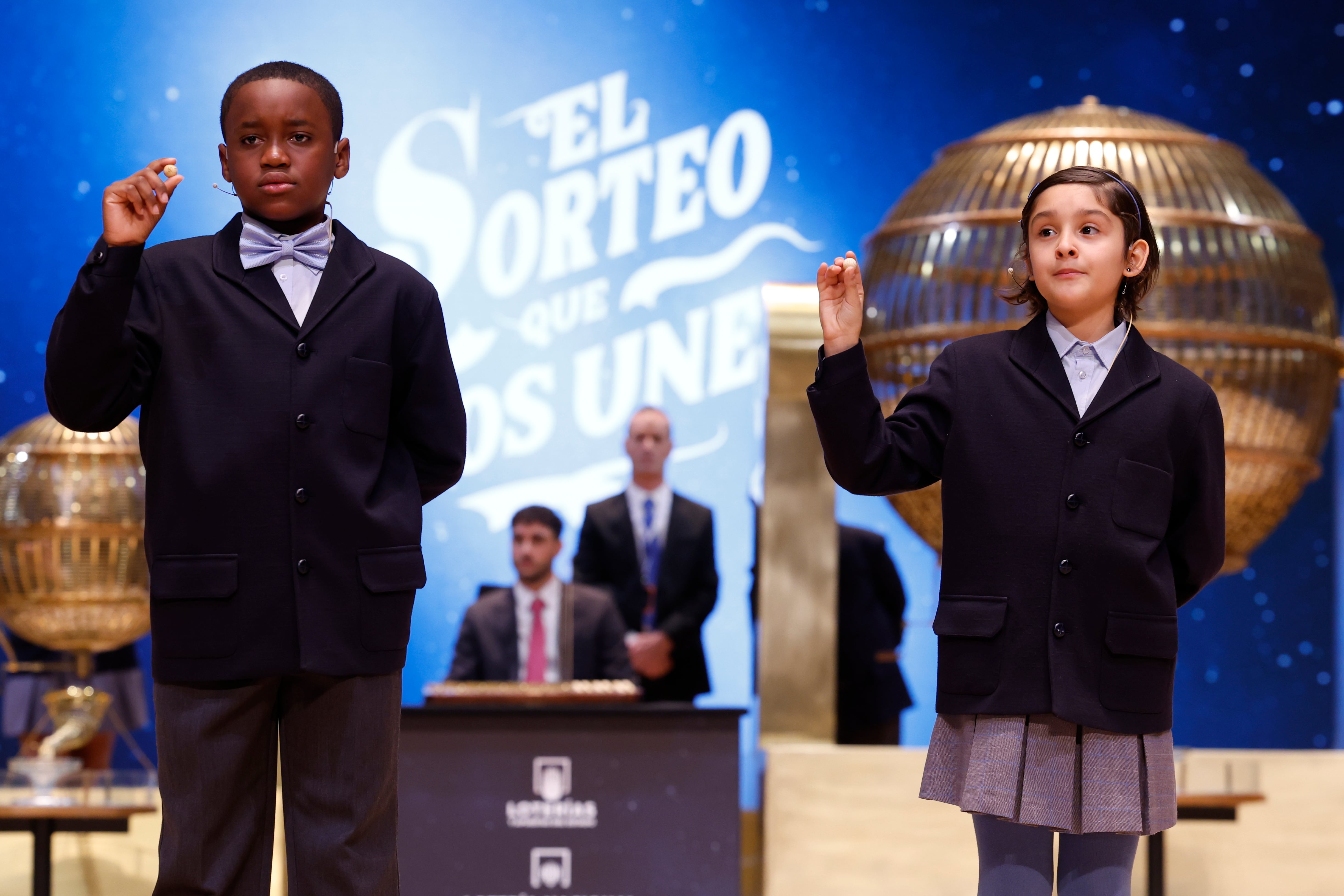 MADRID, 22/12/2024.- Los niños de la Residencia San Ildefonso de Madrid Ángel Abaga Elebiyo (i) y Aurora Rodríguez Ososrio (d) muestran el número 72853, uno de los quintos premios, durante el sorteo de la Lotería de Navidad que se celebra este domingo en el Teatro Real, en Madrid. EFE/Javier Lizón
