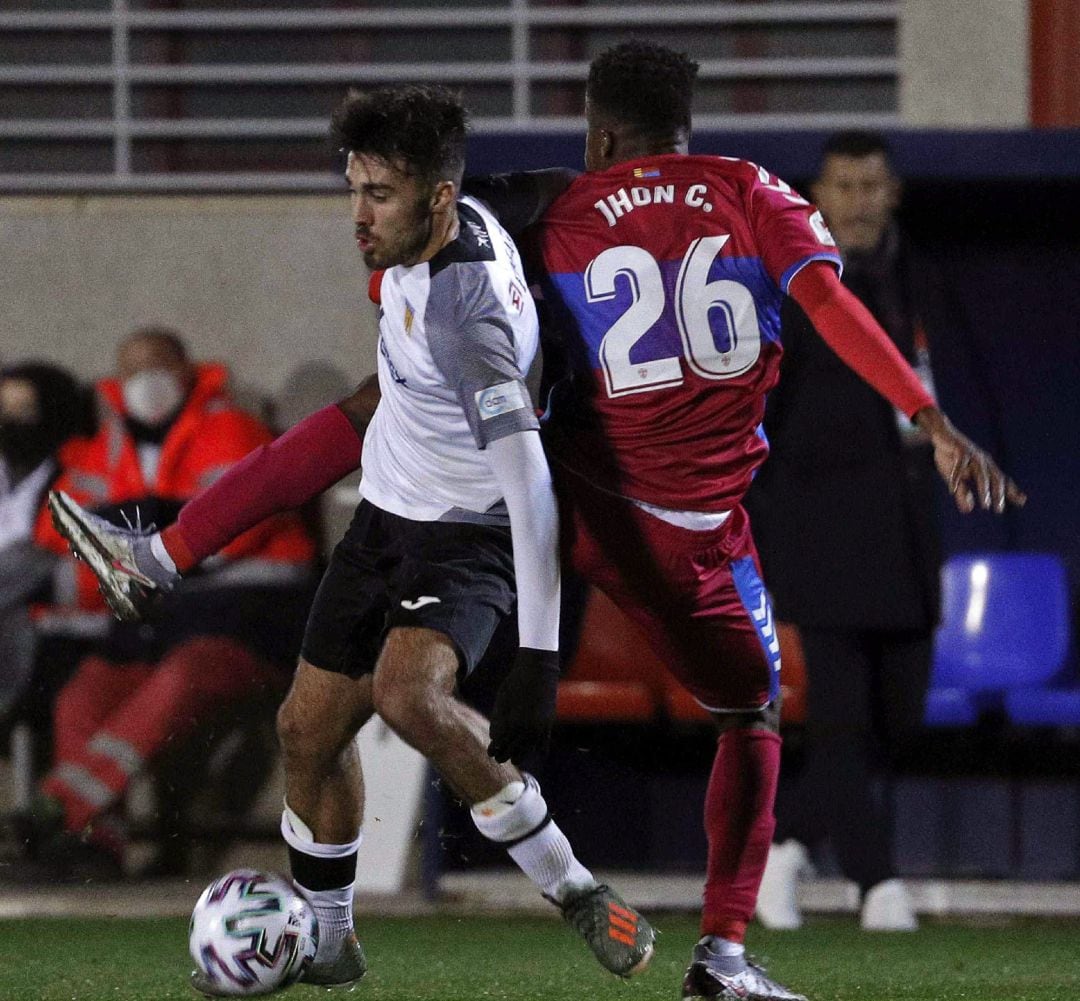 El jugador del CD Buñol Miguel Angel Pastor, disputa un balón con el jugador del Elche CF, John Nwank 